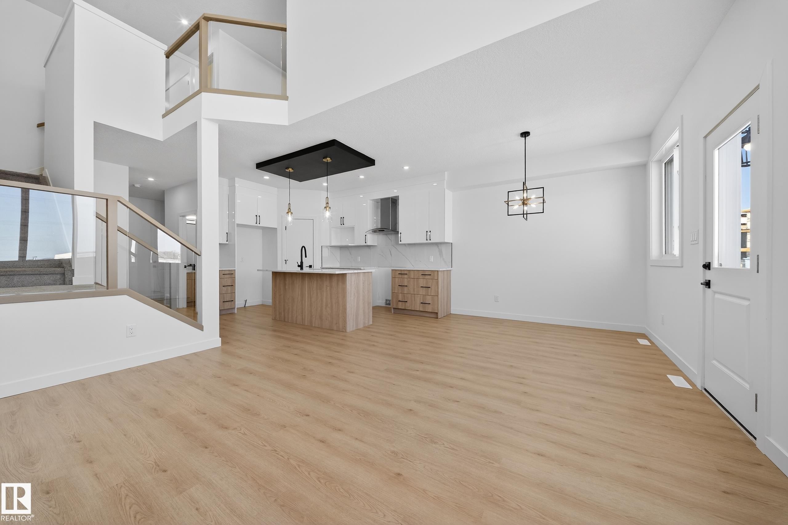 Unfurnished living room with light wood finished floors, a high ceiling, and hanging lights - 129 Pierwyck Loop, Spruce Grove, AB - Indoor Photo Showing Other Room