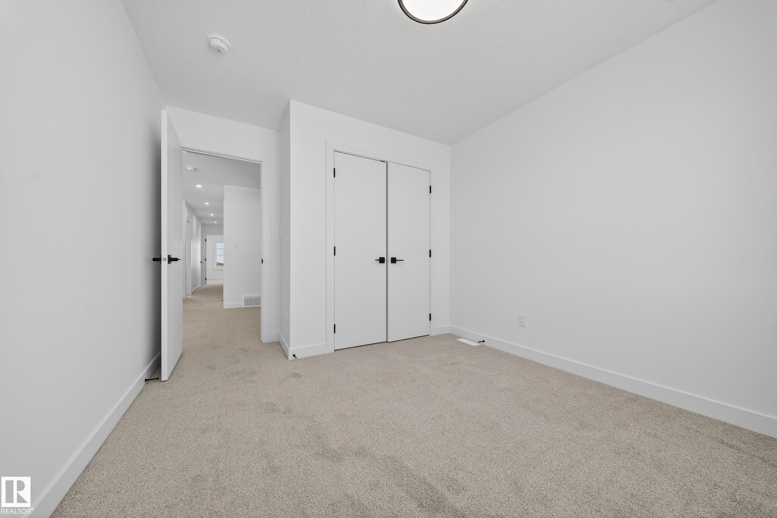Unfurnished bedroom featuring light colored carpet and a closet - 129 Pierwyck Loop, Spruce Grove, AB - Indoor Photo Showing Other Room