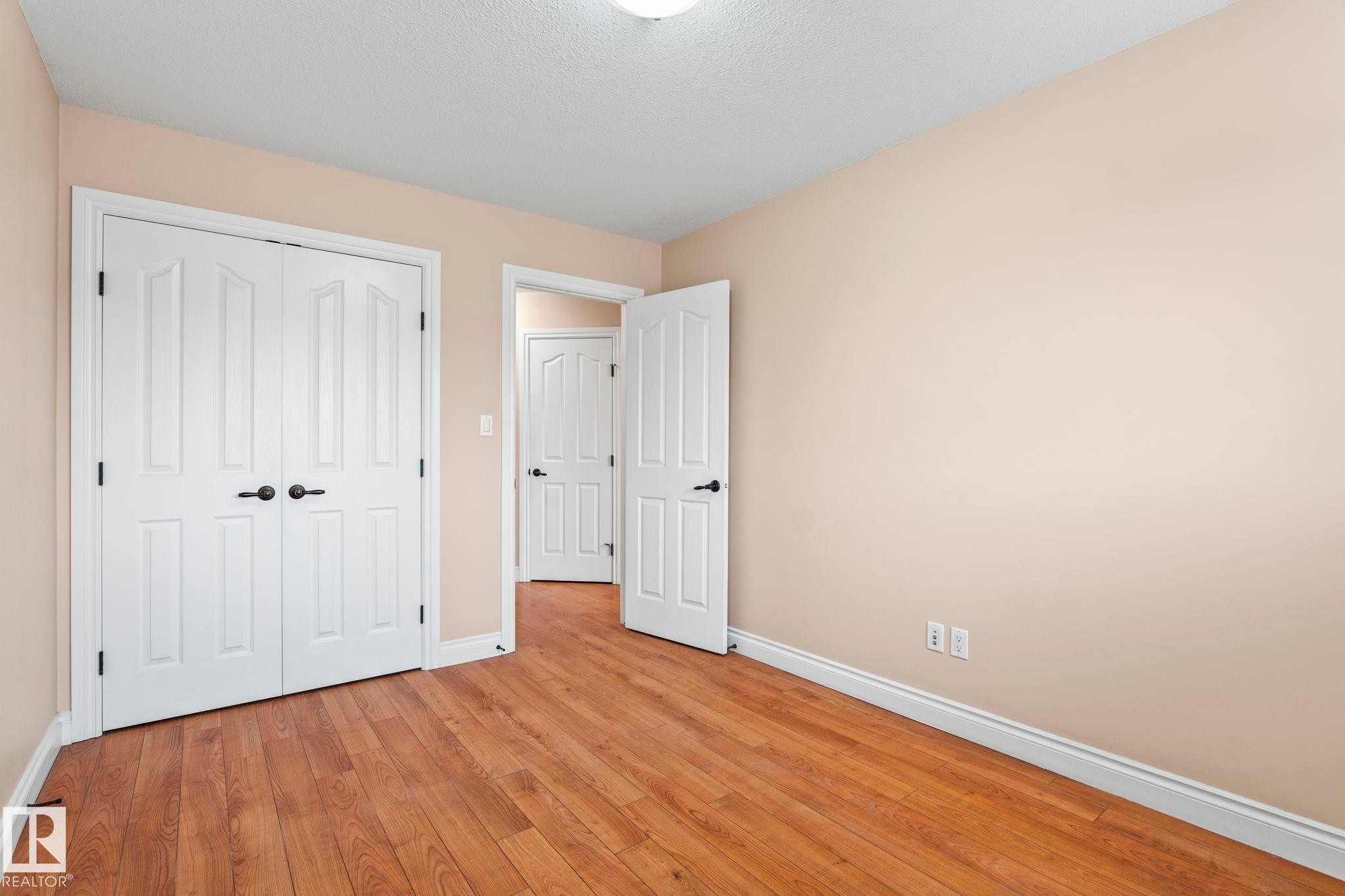 Unfurnished bedroom with wood finished floors, a textured ceiling, and a closet - 1888 33 Street, Edmonton, AB - Indoor Photo Showing Other Room