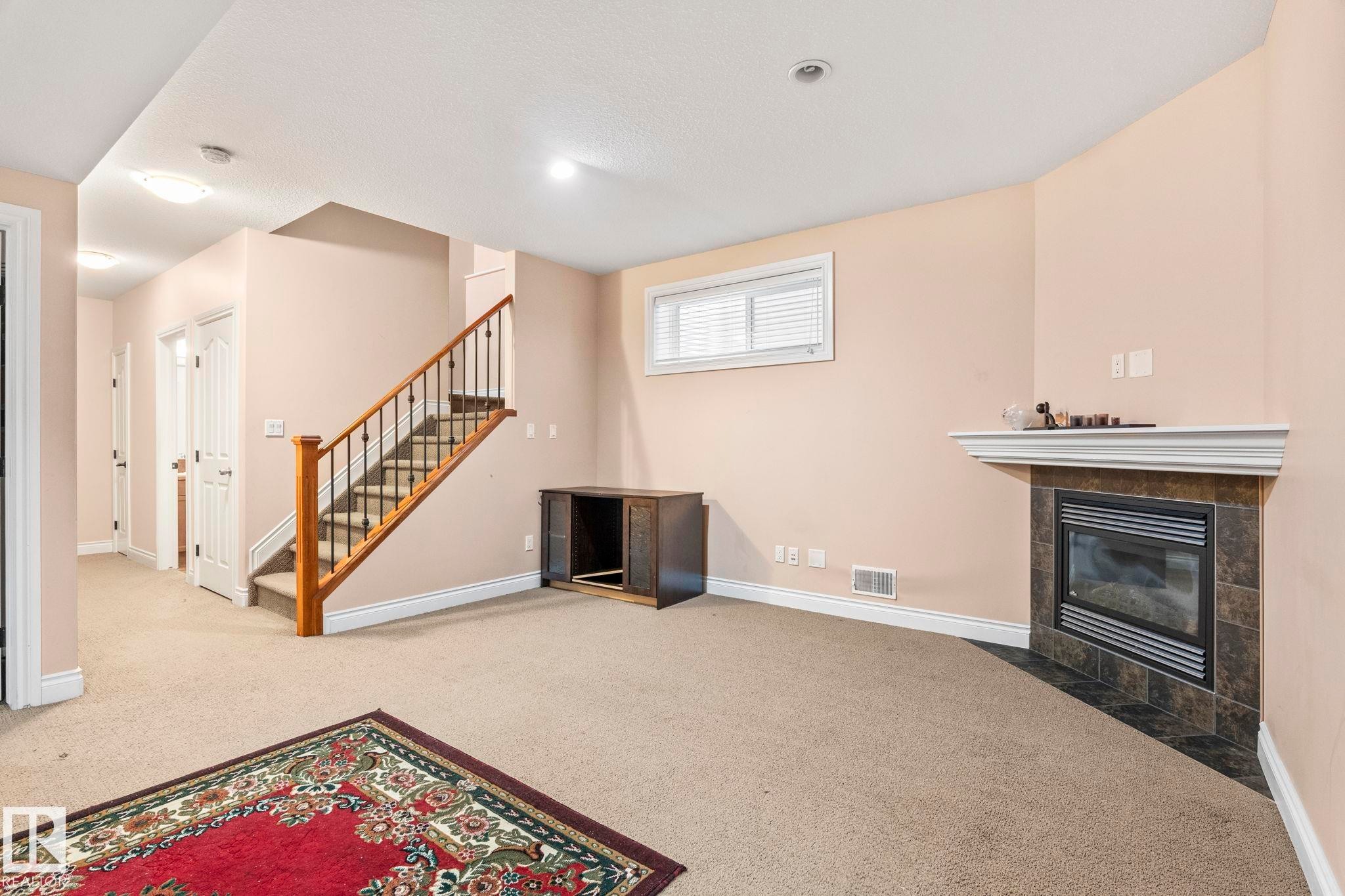 Unfurnished living room featuring a tile fireplace, carpet flooring, and stairs - 1888 33 Street, Edmonton, AB - Indoor With Fireplace