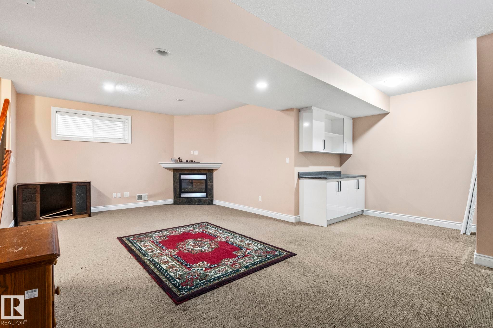 Basement with a glass covered fireplace and light carpet - 1888 33 Street, Edmonton, AB - Indoor With Fireplace