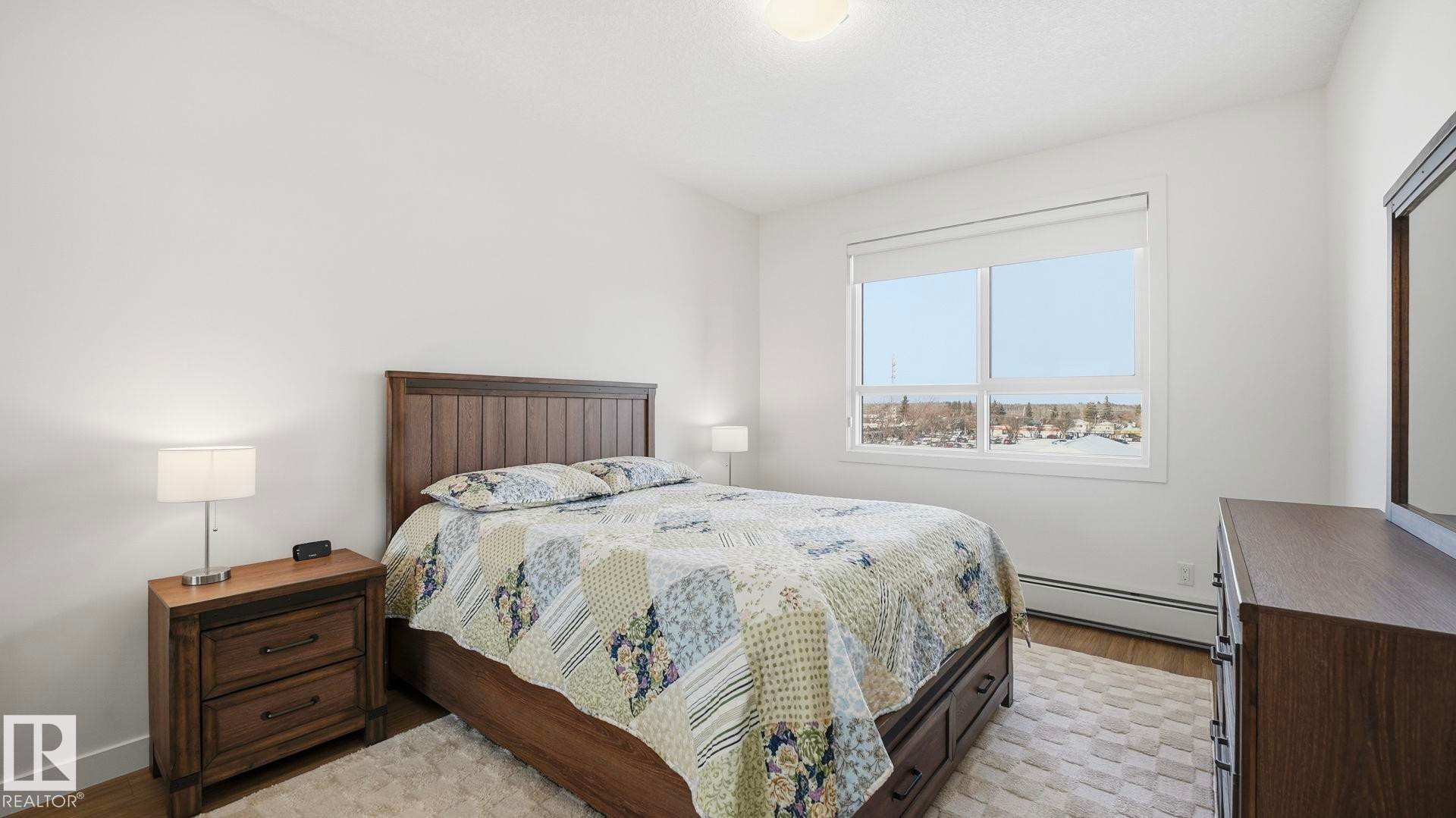 Bedroom with baseboard heating and light wood-type flooring - 401 17 Columbia Avenue W, Devon, AB - Indoor Photo Showing Bedroom