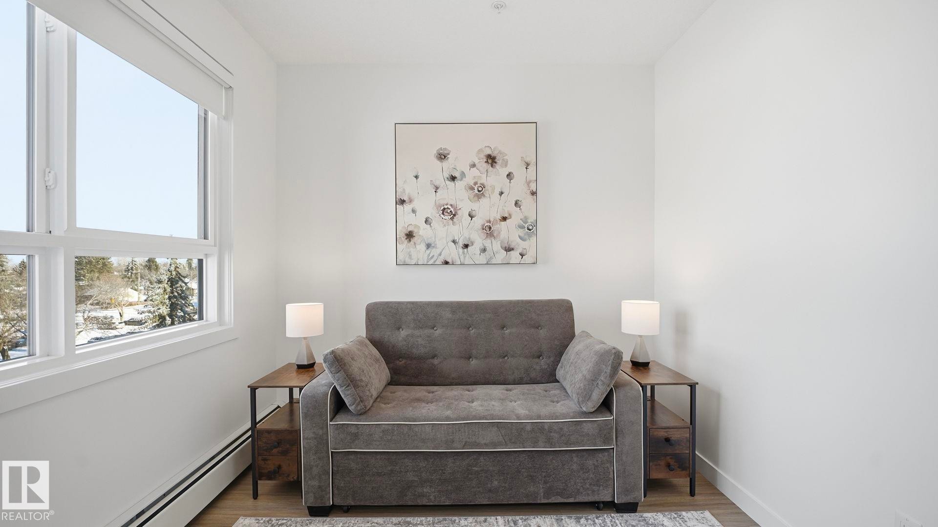 Living area featuring a baseboard heating unit and wood finished floors - 401 17 Columbia Avenue W, Devon, AB - Indoor Photo Showing Bedroom