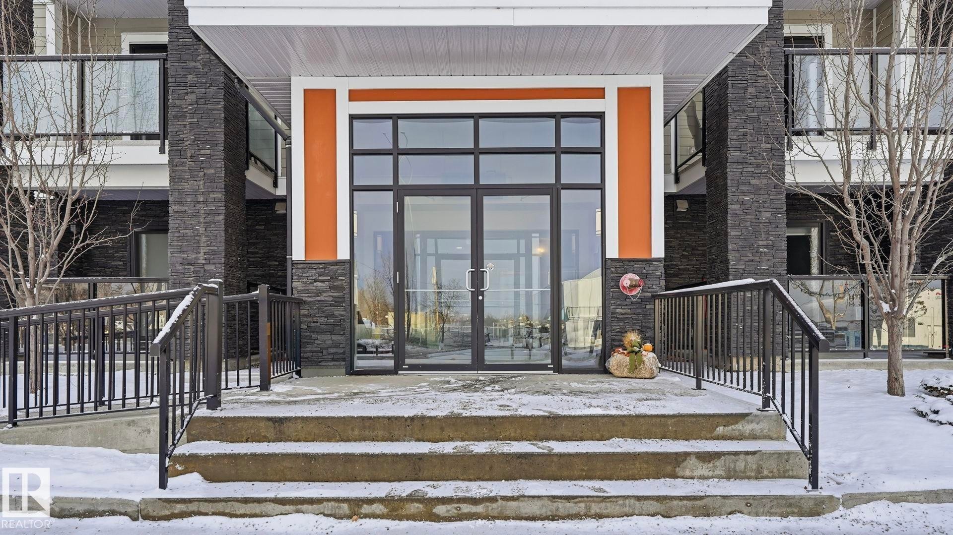 Snow covered property entrance with stone siding and french doors - 401 17 Columbia Avenue W, Devon, AB - Outdoor