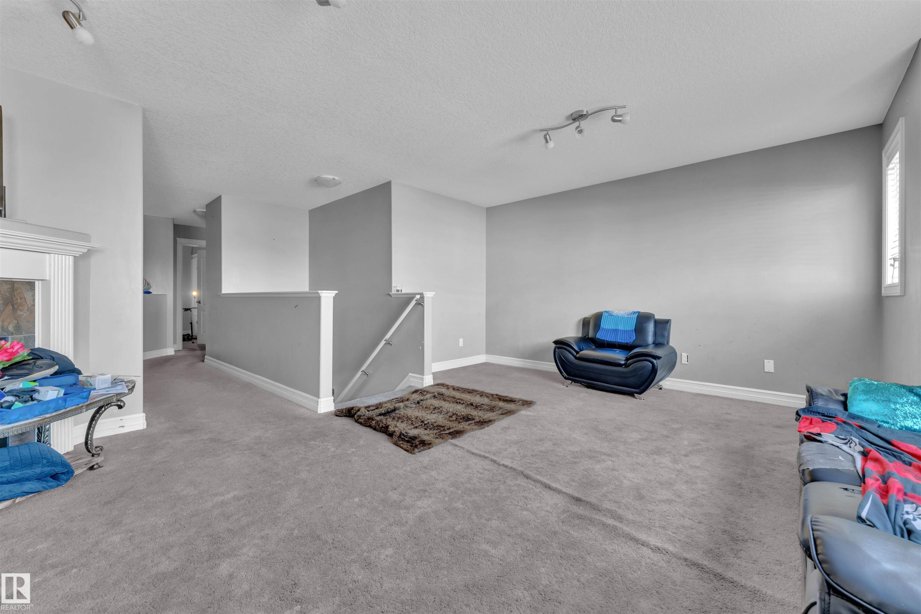 Unfurnished room featuring an upstairs landing, a textured ceiling, carpet, and rail lighting - 3015 26 Ave Nw, Edmonton, AB - Indoor