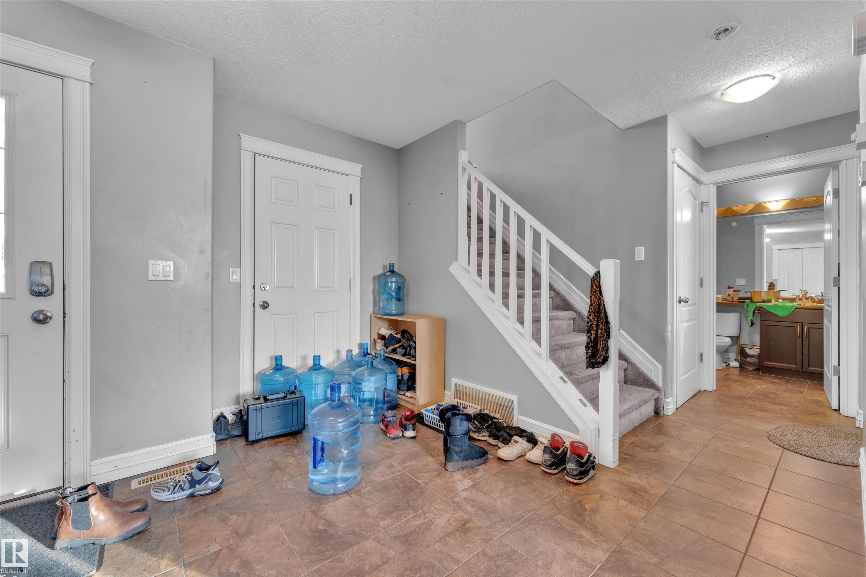 Foyer featuring a textured ceiling, stairs, and tile patterned flooring - 3015 26 Ave Nw, Edmonton, AB - Indoor Photo Showing Other Room