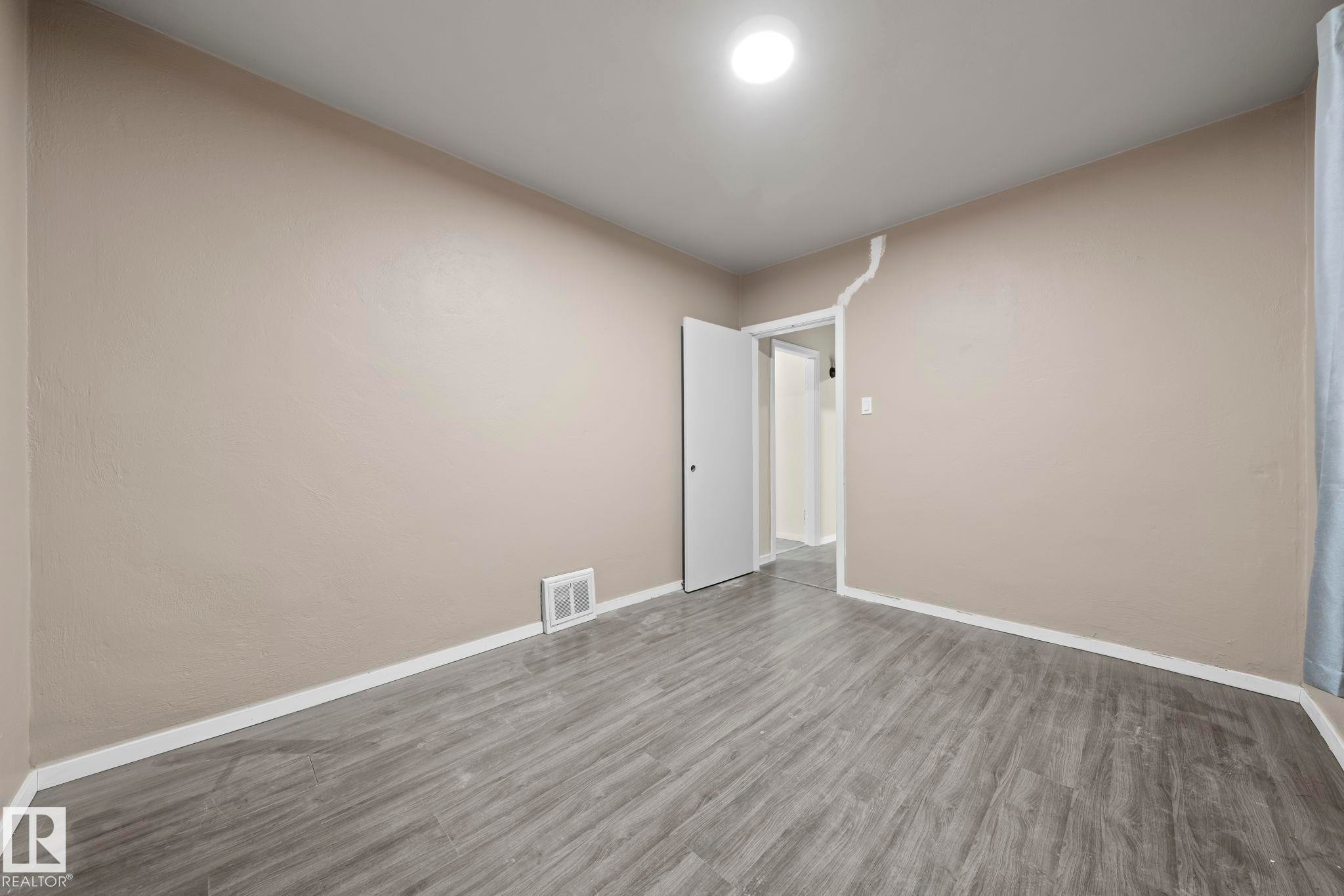 Empty room featuring baseboards and wood finished floors - Edmonton, AB - Indoor Photo Showing Other Room