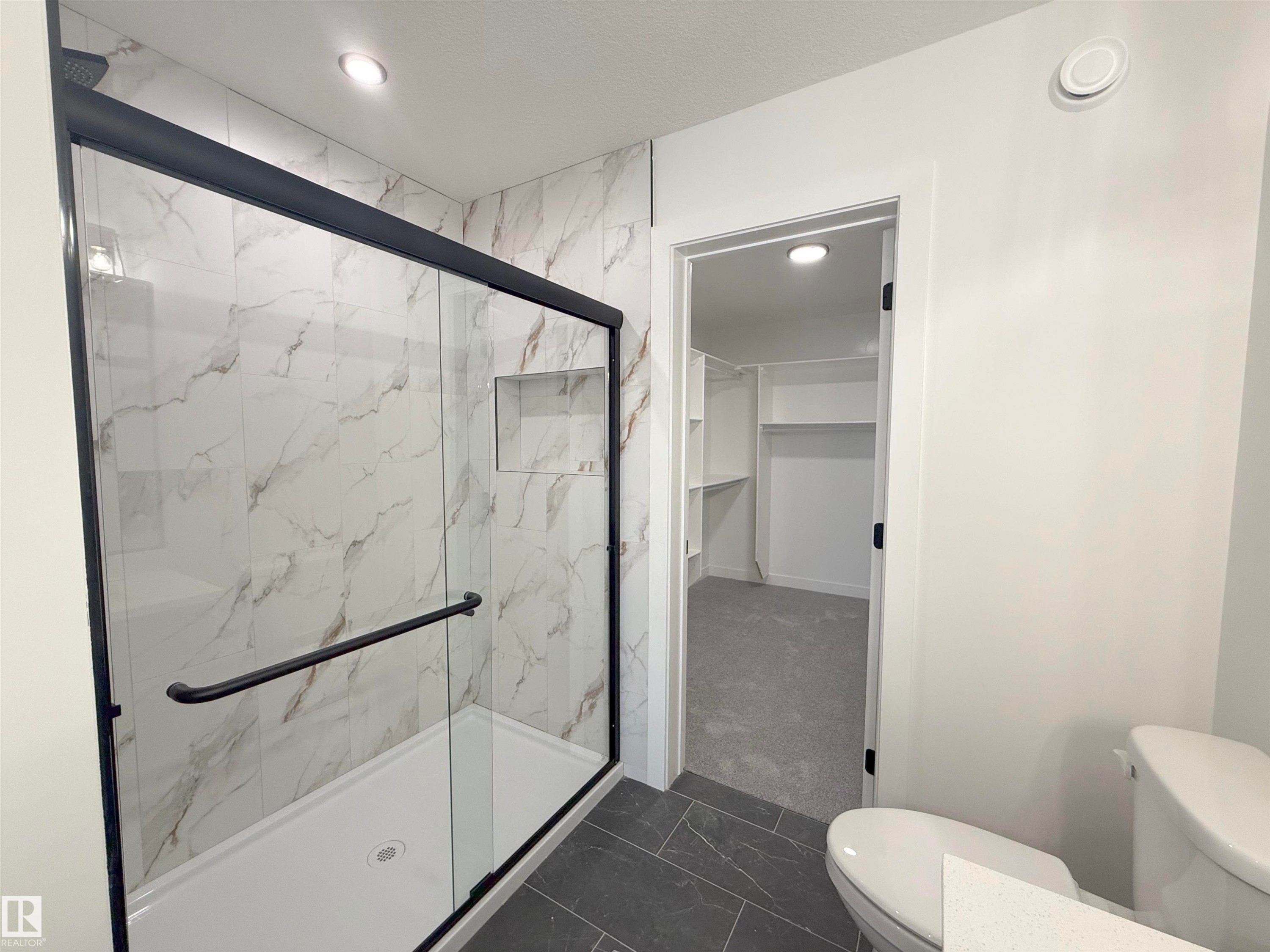 Bathroom with dark marble finish floors, a marble finish shower, a spacious closet, and recessed lighting - 3158 Magpie Way, Edmonton, AB - Indoor Photo Showing Bathroom