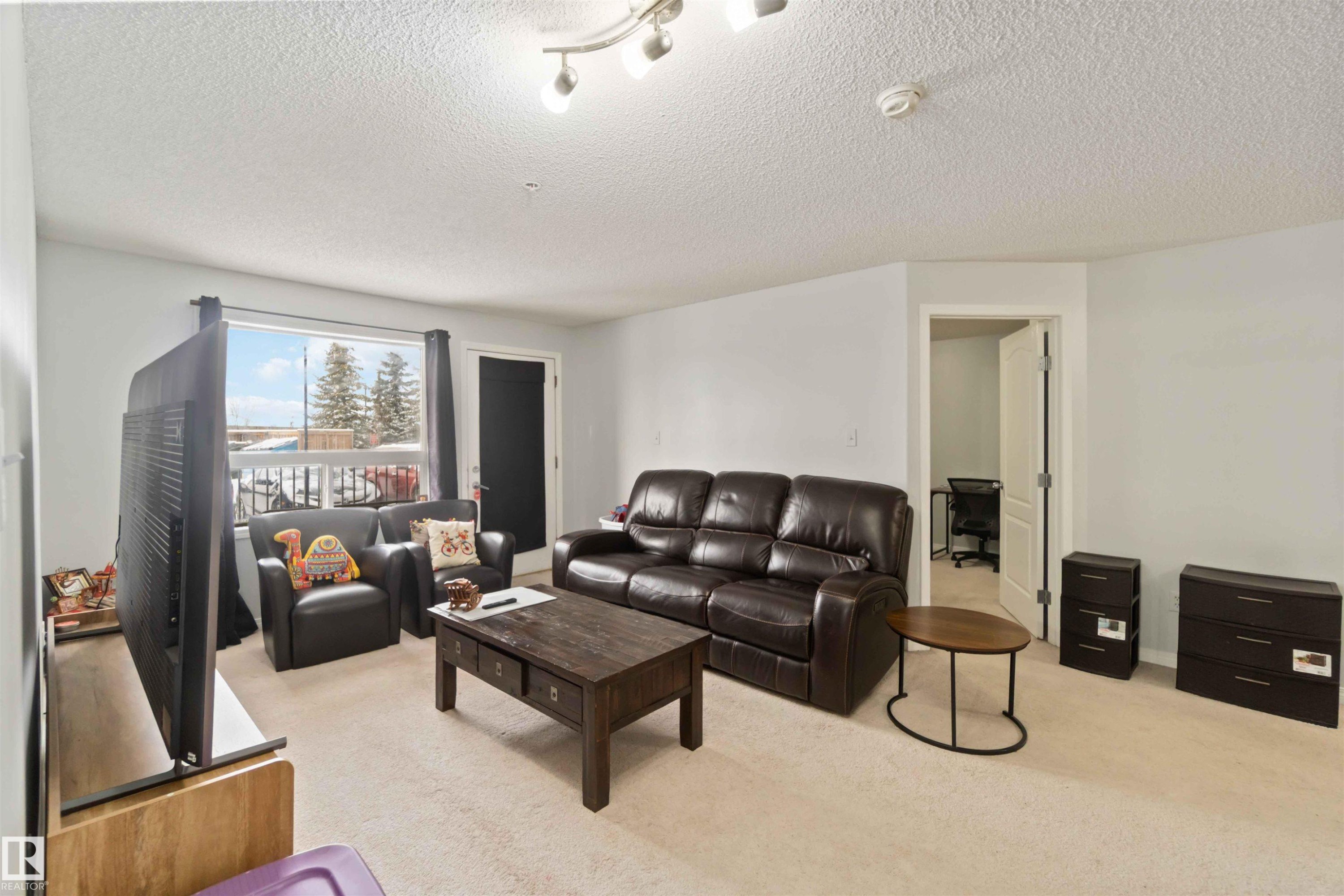 Living area with light carpet and a textured ceiling - 2117 9357 Simpson Drive, Edmonton, AB - Indoor Photo Showing Living Room