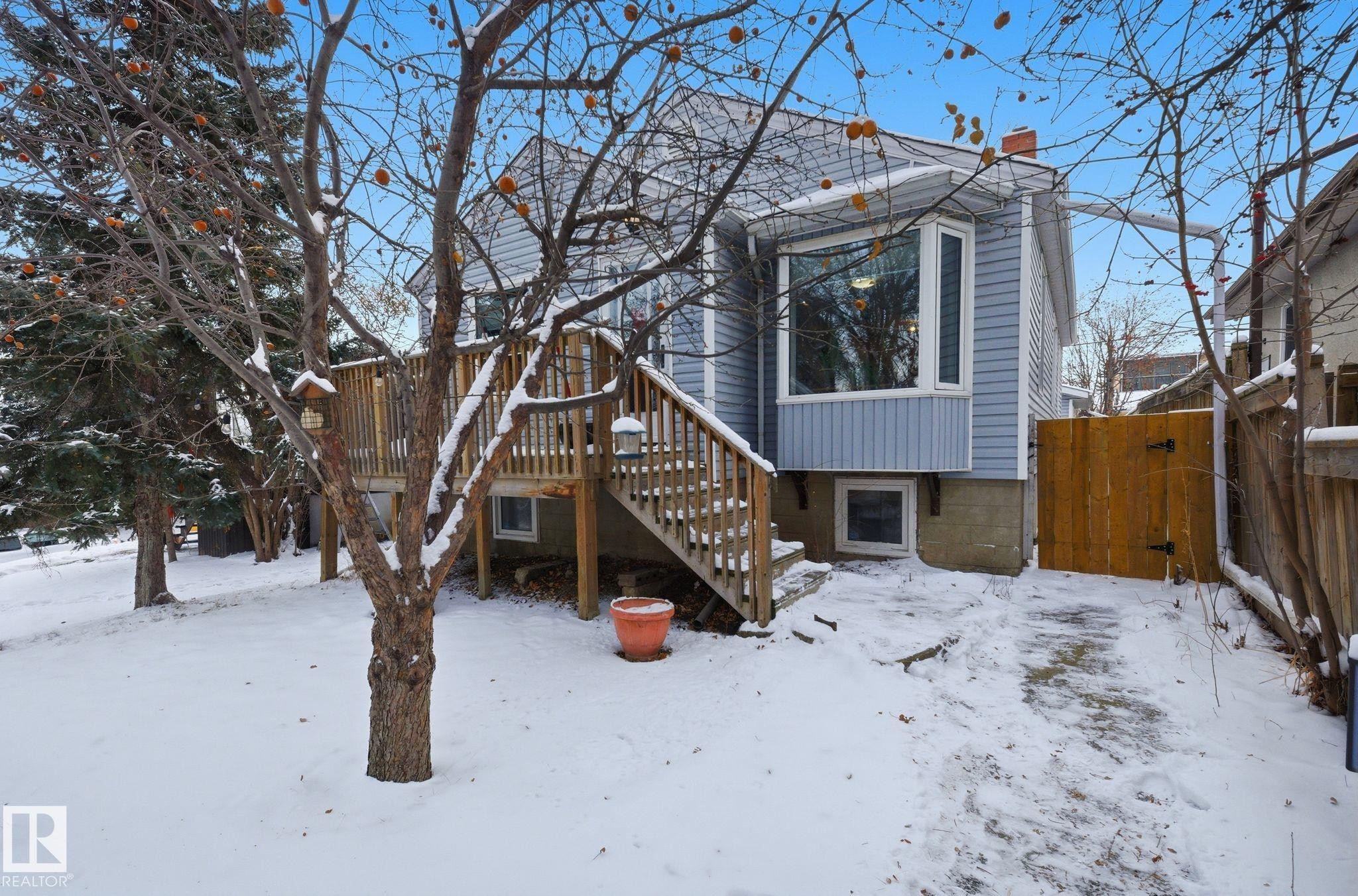 View of front of home with a chimney, a wooden deck, a gate, and stairway - 9705 87 Avenue, Edmonton, AB - Outdoor