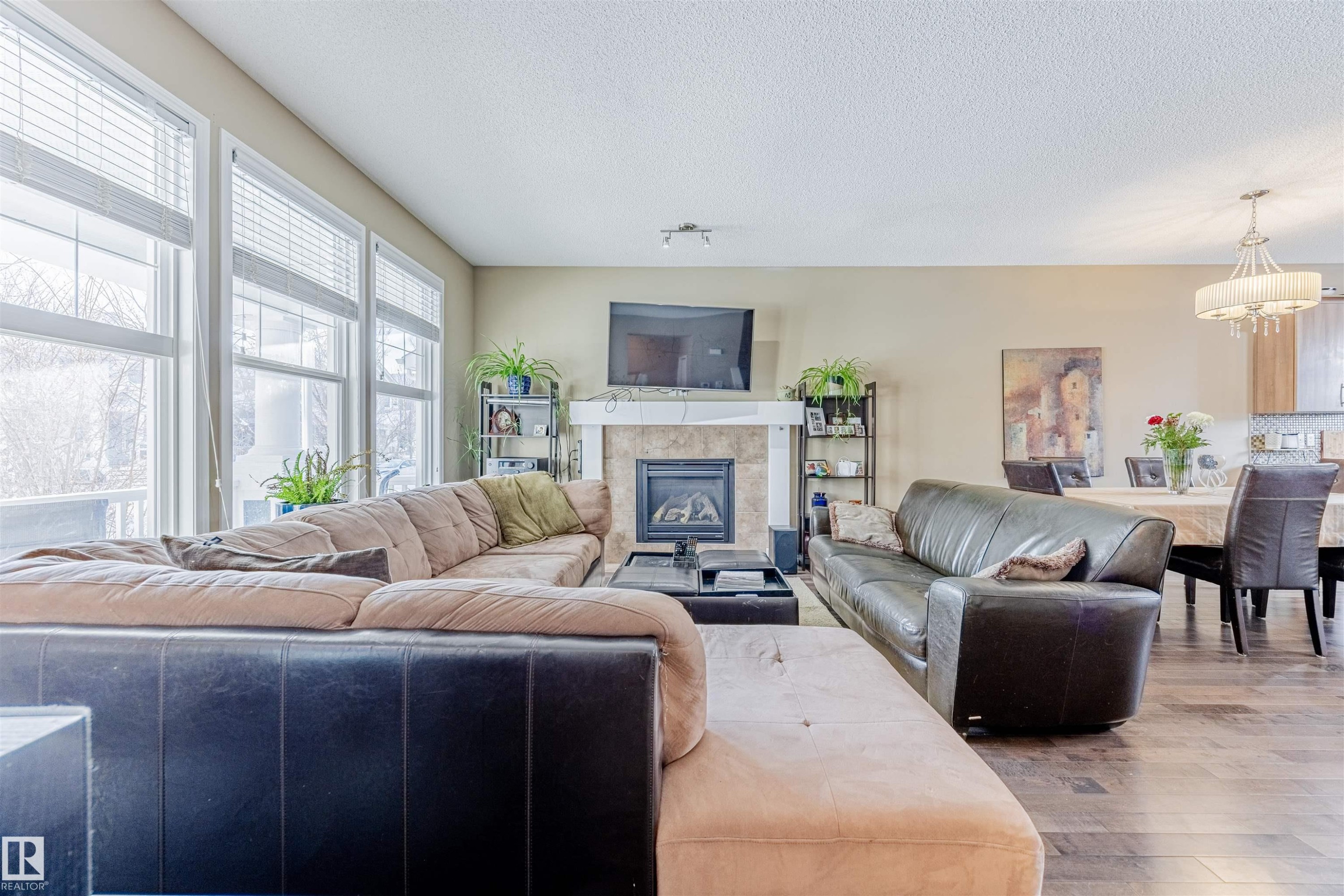 Living area featuring large windows letting in loads of natural light, a fireplace with mantel & tile surround & hardwood flooring. - 1312 74 Street, Edmonton, AB - Indoor Photo Showing Living Room With Fireplace