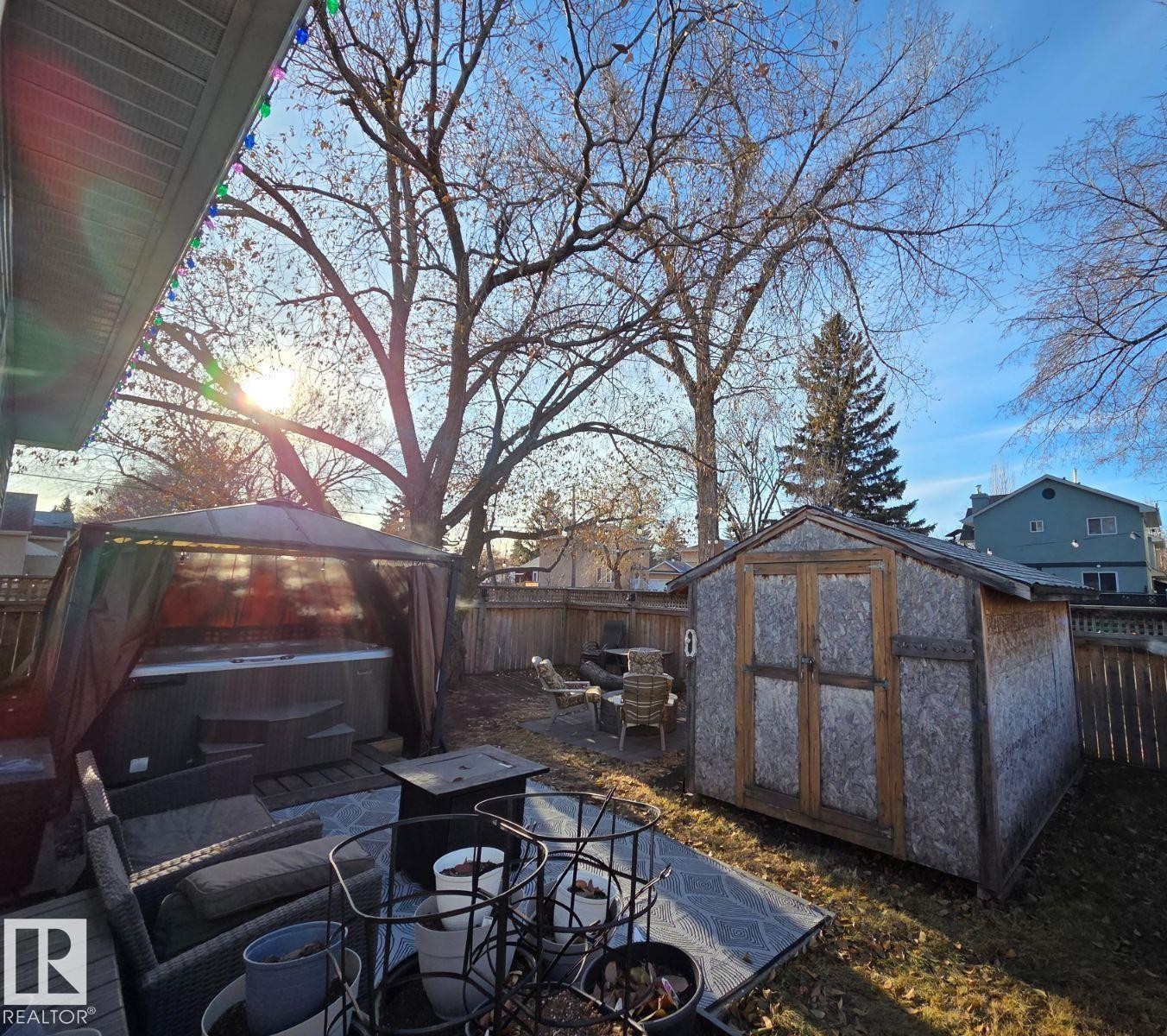 Fenced backyard featuring a hot tub, a gazebo, an outdoor fire pit, and a shed - 12410 120 Avenue, Edmonton, AB - Outdoor