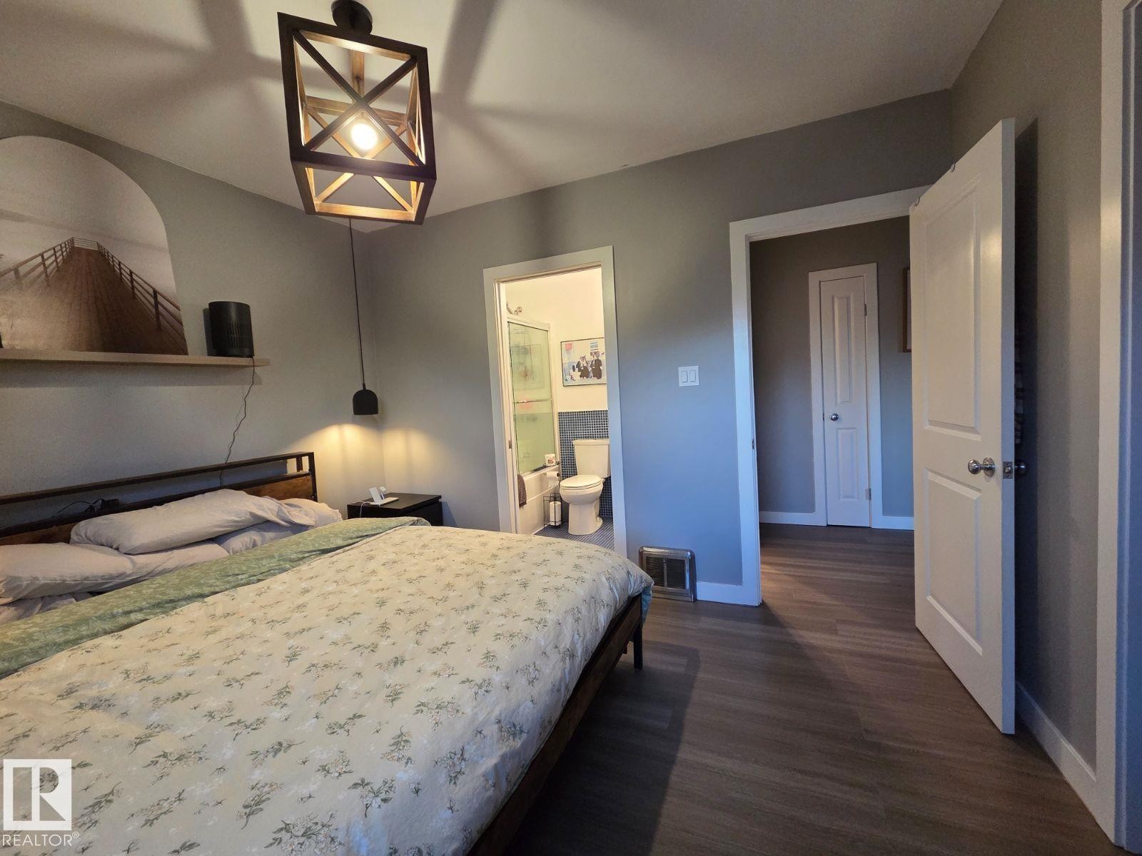 Bedroom with dark wood finished floors and connected bathroom - 12410 120 Avenue, Edmonton, AB - Indoor Photo Showing Bedroom