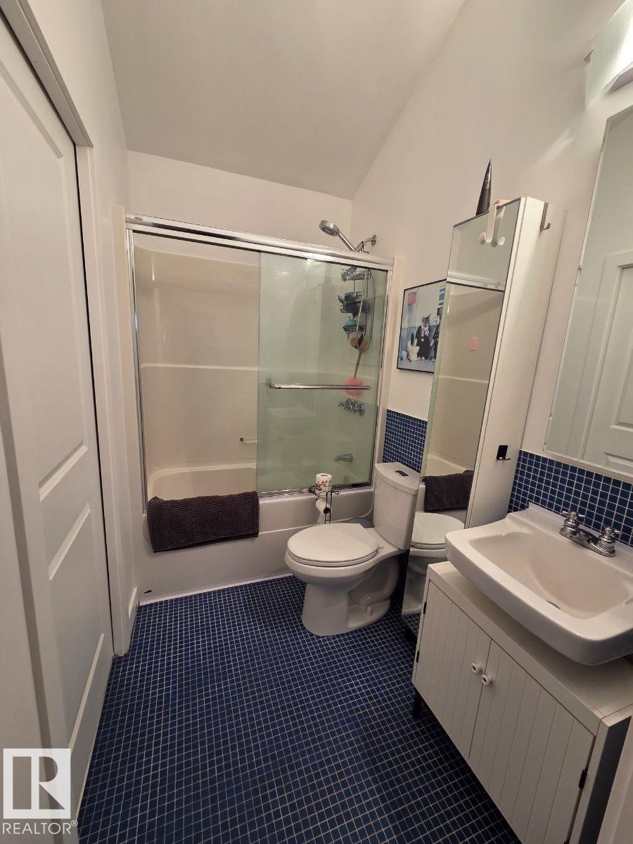Bathroom with vanity, bath / shower combo with glass door, and dark tile patterned floors - 12410 120 Avenue, Edmonton, AB - Indoor Photo Showing Bathroom