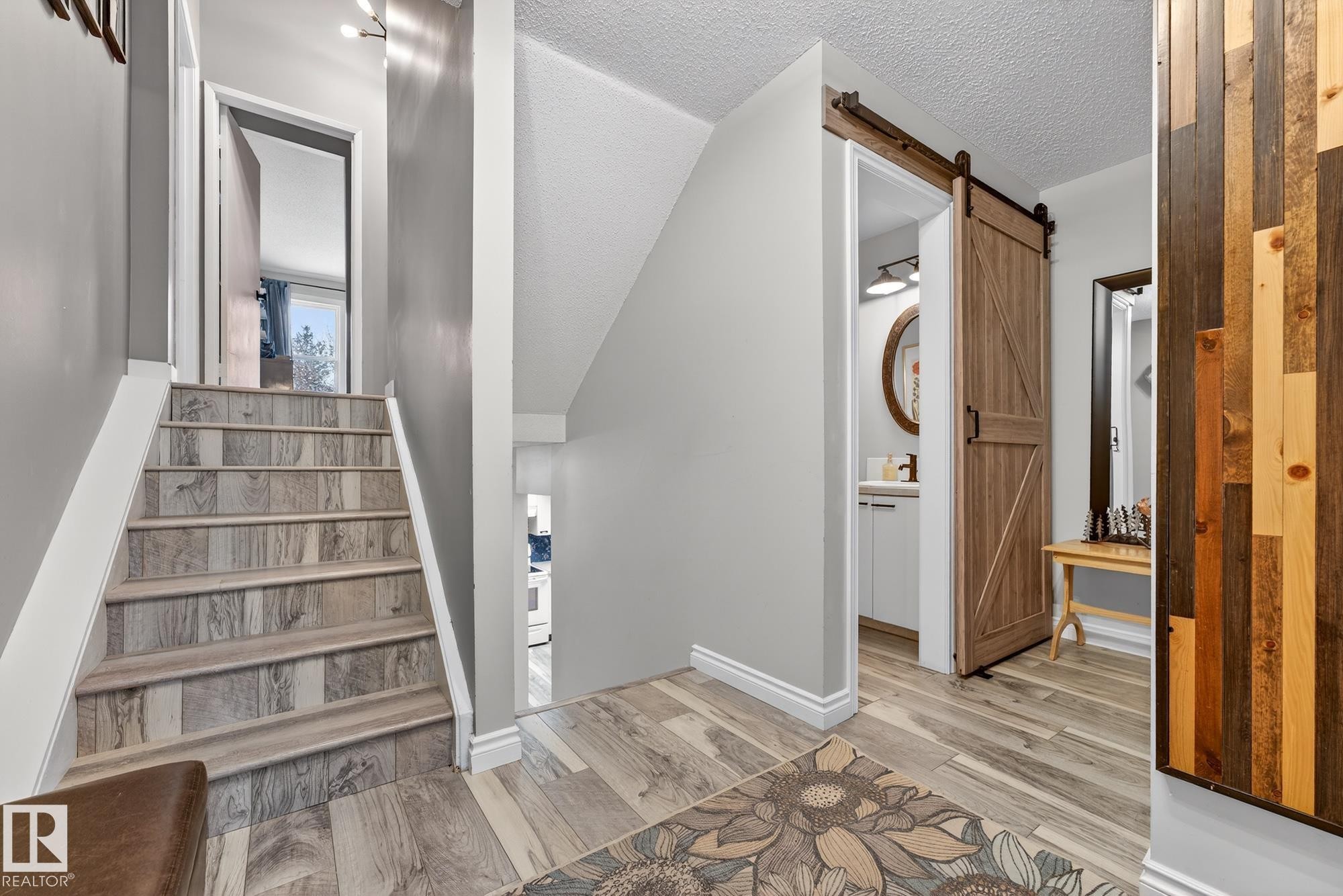 Stairs featuring a textured ceiling, wood finished floors, and a barn door - 7 Grandview Ridge, St. Albert, AB - Indoor Photo Showing Other Room