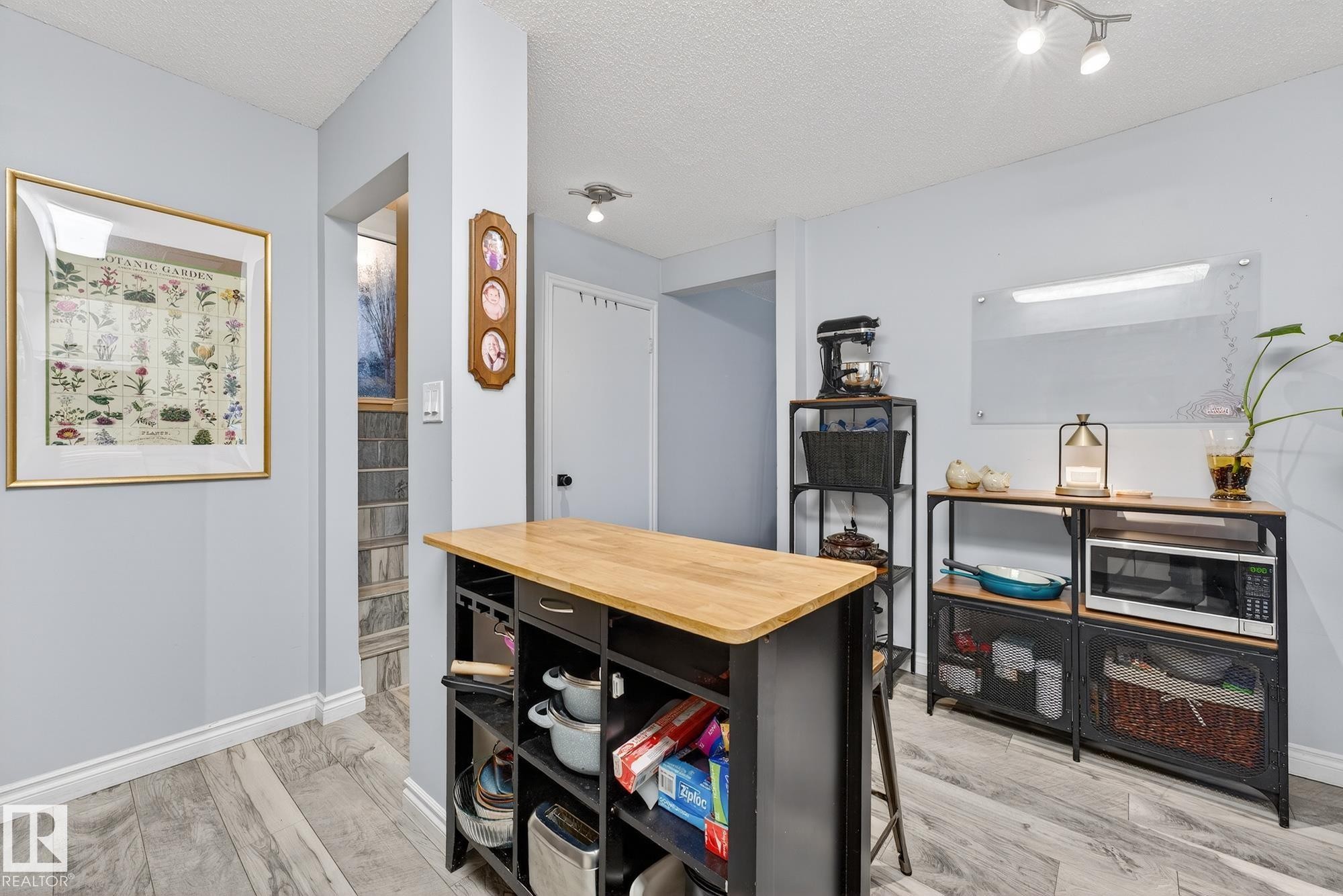 Kitchen with butcher block countertops, a textured ceiling, stainless steel microwave, and light wood-style floors - 7 Grandview Ridge, St. Albert, AB - Indoor Photo Showing Other Room