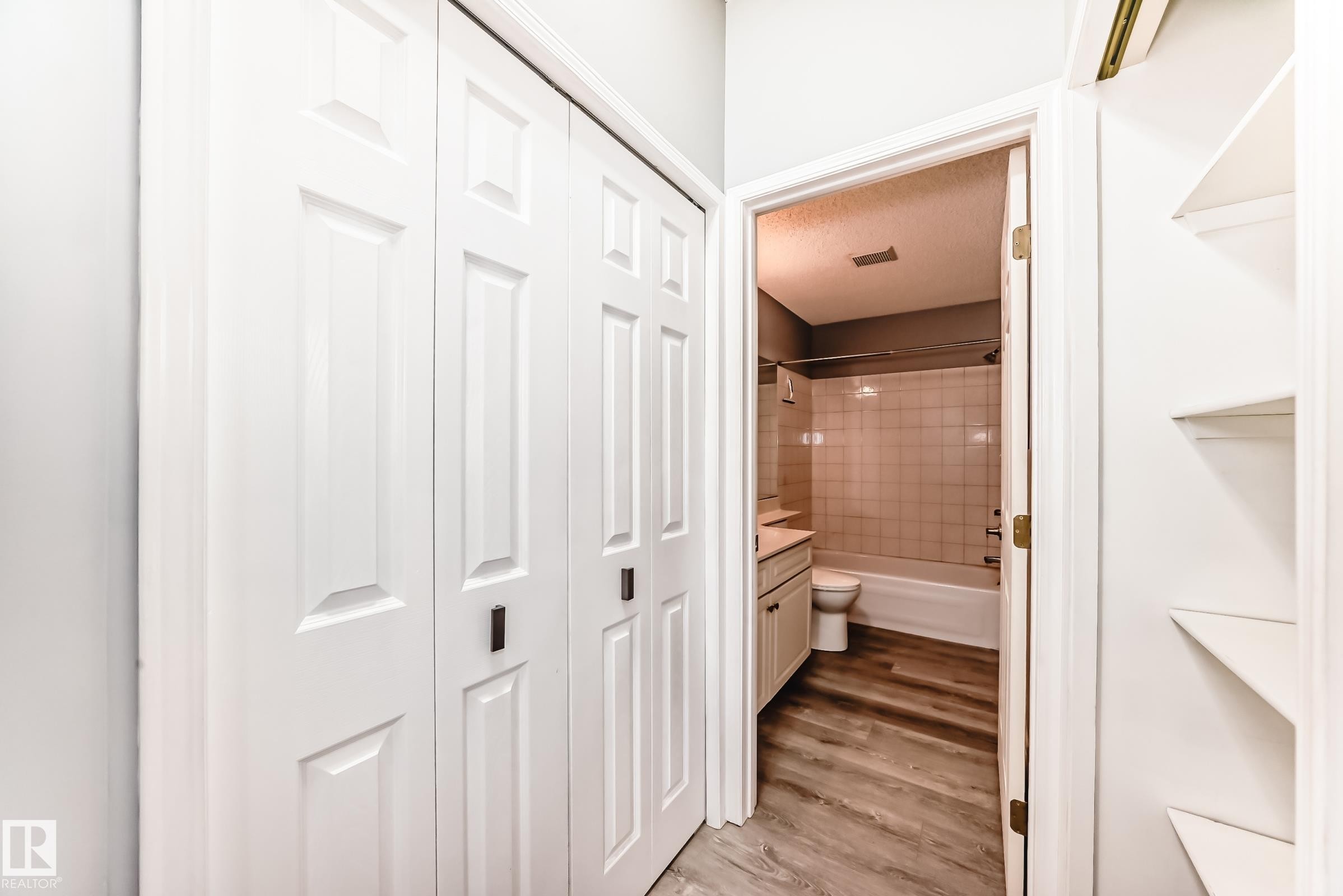 Bathroom featuring a closet, vanity, light wood-type flooring, bathtub / shower combination, and a textured ceiling - 507 11716 100 Avenue, Edmonton, AB - Indoor Photo Showing Other Room
