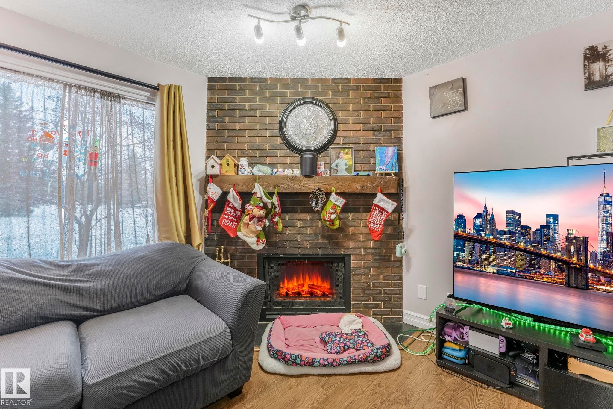 Living room featuring a fireplace, wood finished floors, and a textured ceiling - 11811 32A Avenue, Edmonton, AB - Indoor With Fireplace