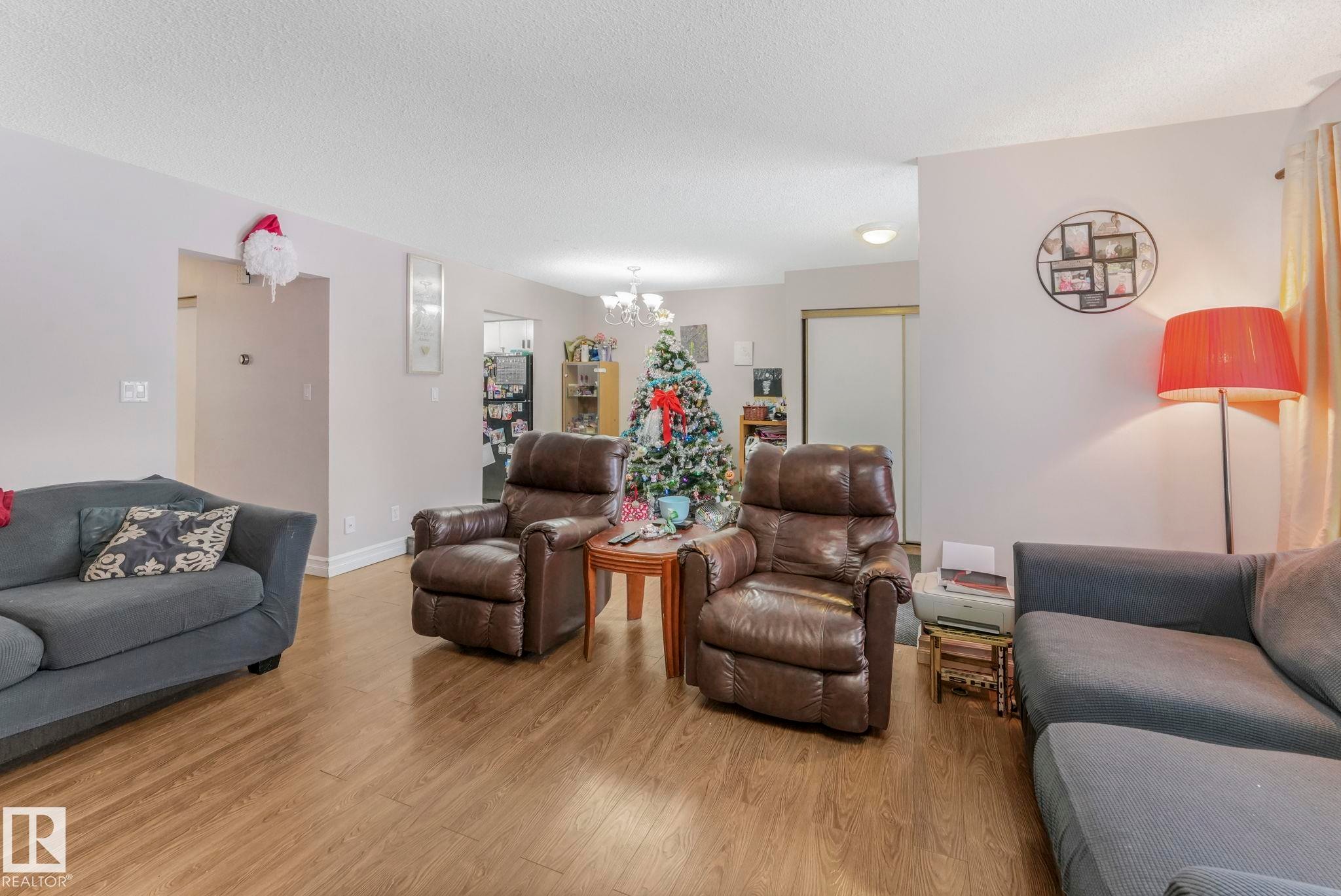 Living area with a chandelier, wood finished floors, and a textured ceiling - 11811 32A Avenue, Edmonton, AB - Indoor Photo Showing Living Room