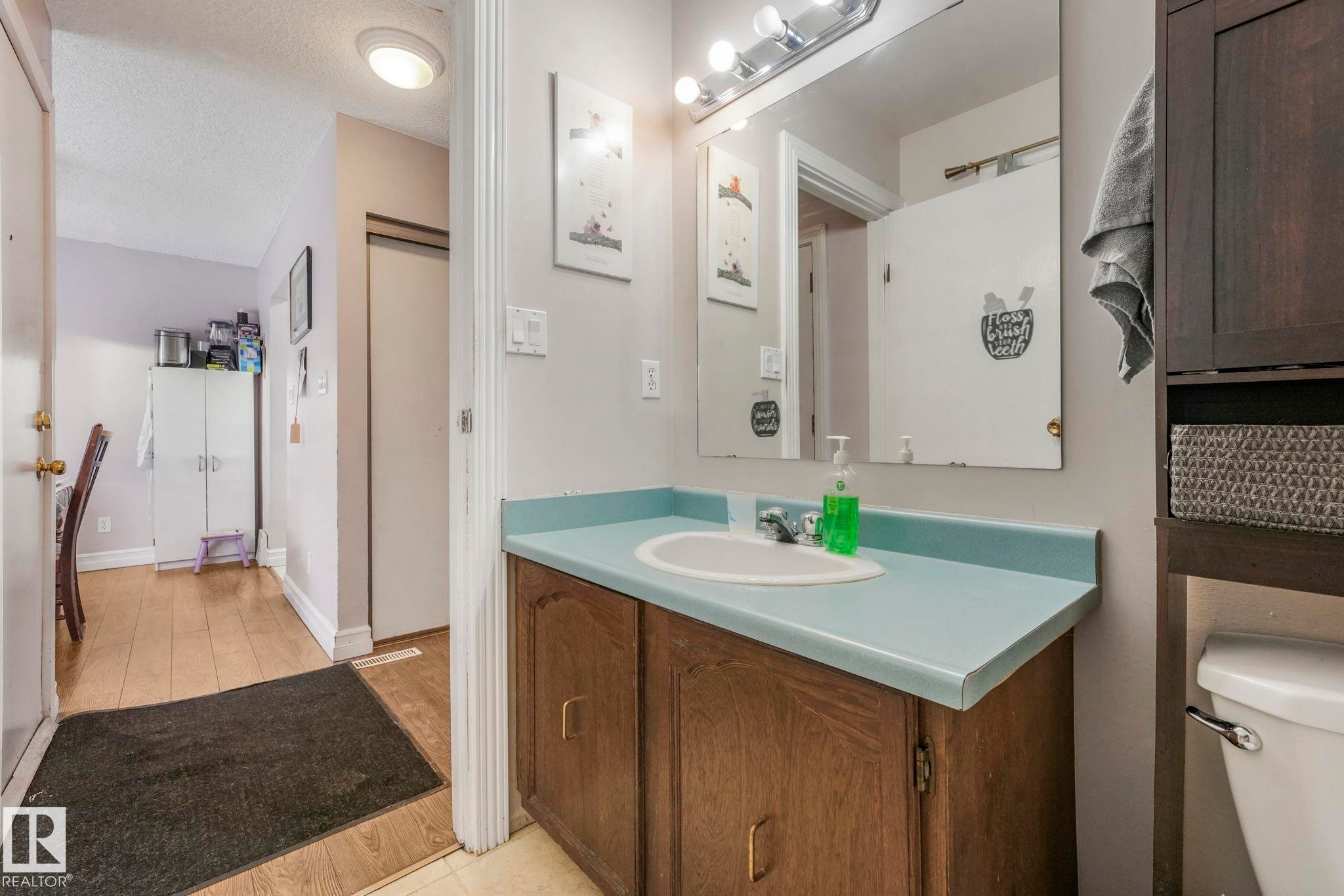 Half bath with a textured ceiling, vanity, and light wood-type flooring - 11811 32A Avenue, Edmonton, AB - Indoor Photo Showing Bathroom