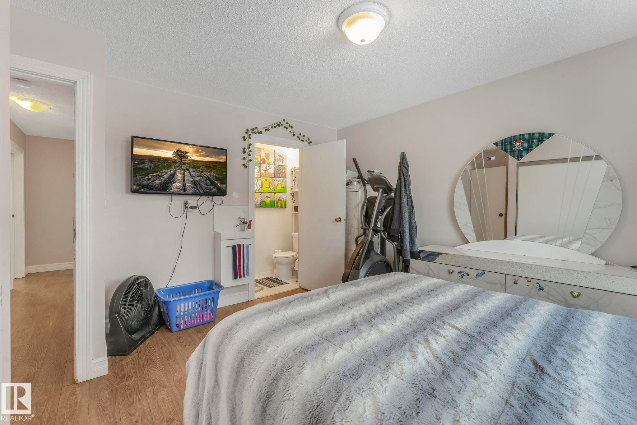Bedroom featuring a textured ceiling, wood finished floors, and connected bathroom - 11811 32A Avenue, Edmonton, AB - Indoor Photo Showing Bedroom