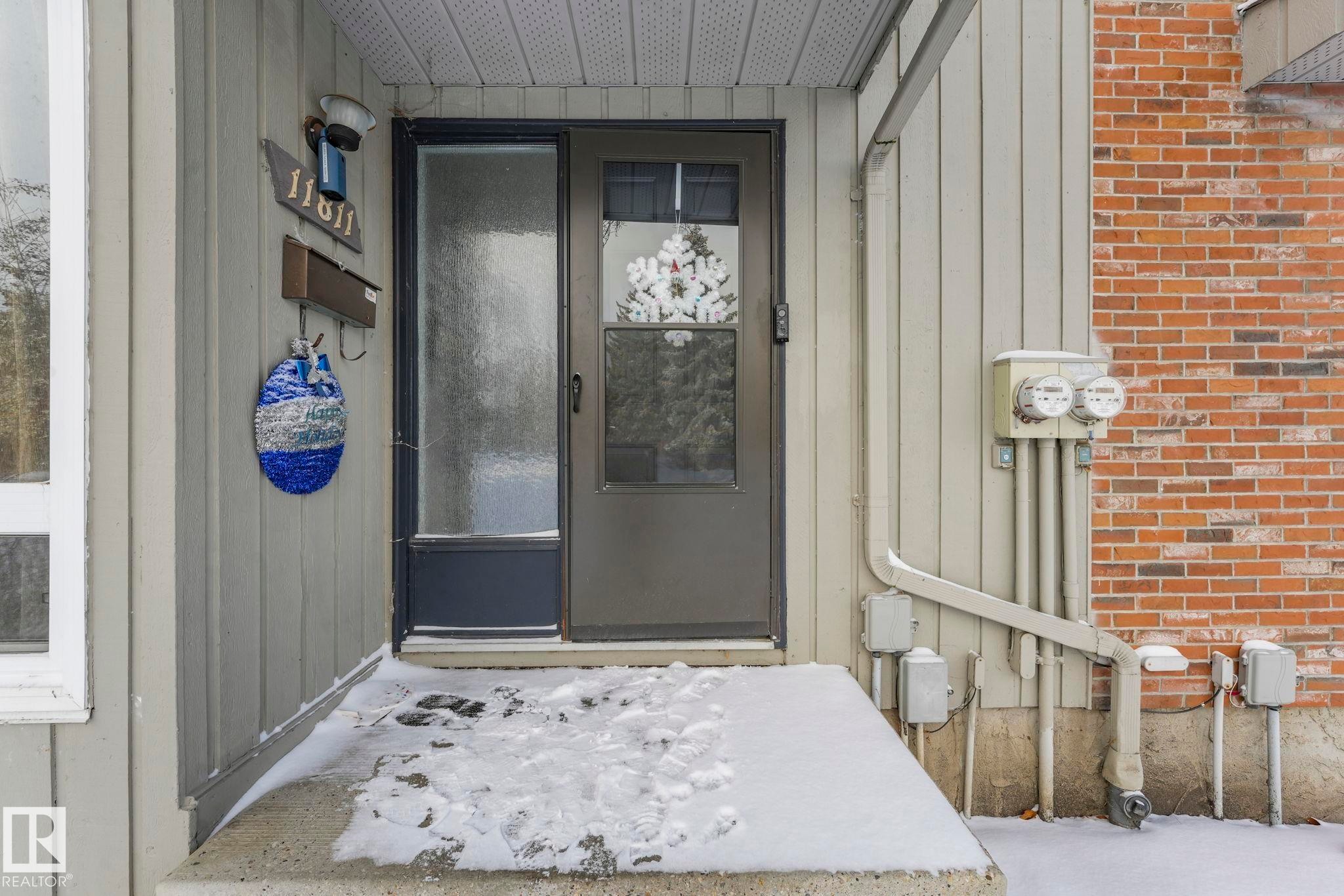 Doorway to property featuring board and batten siding and brick siding - 11811 32A Avenue, Edmonton, AB - Outdoor With Exterior