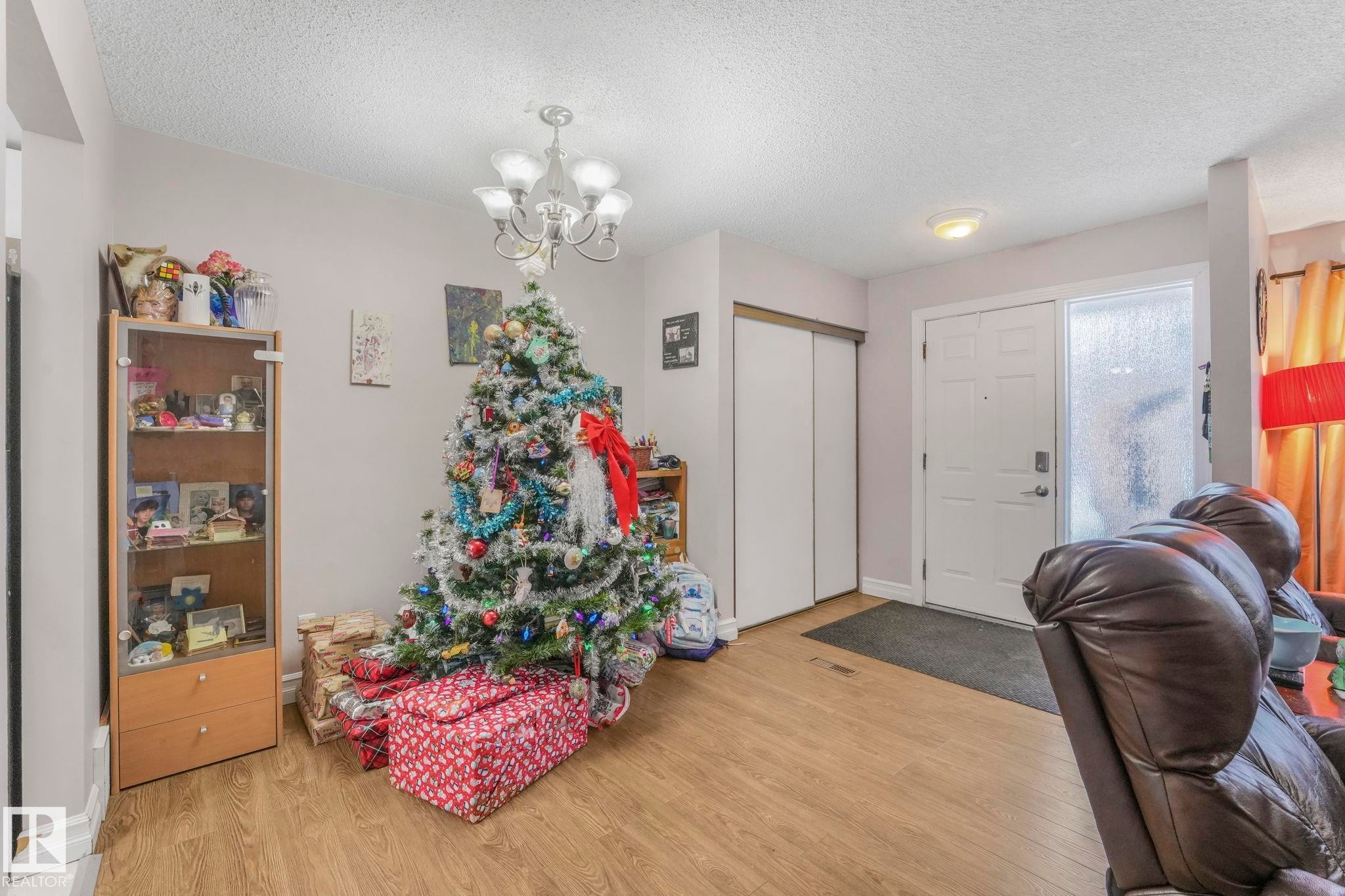 Foyer featuring light wood-style flooring, a textured ceiling, and a chandelier - 11811 32A Avenue, Edmonton, AB - Indoor