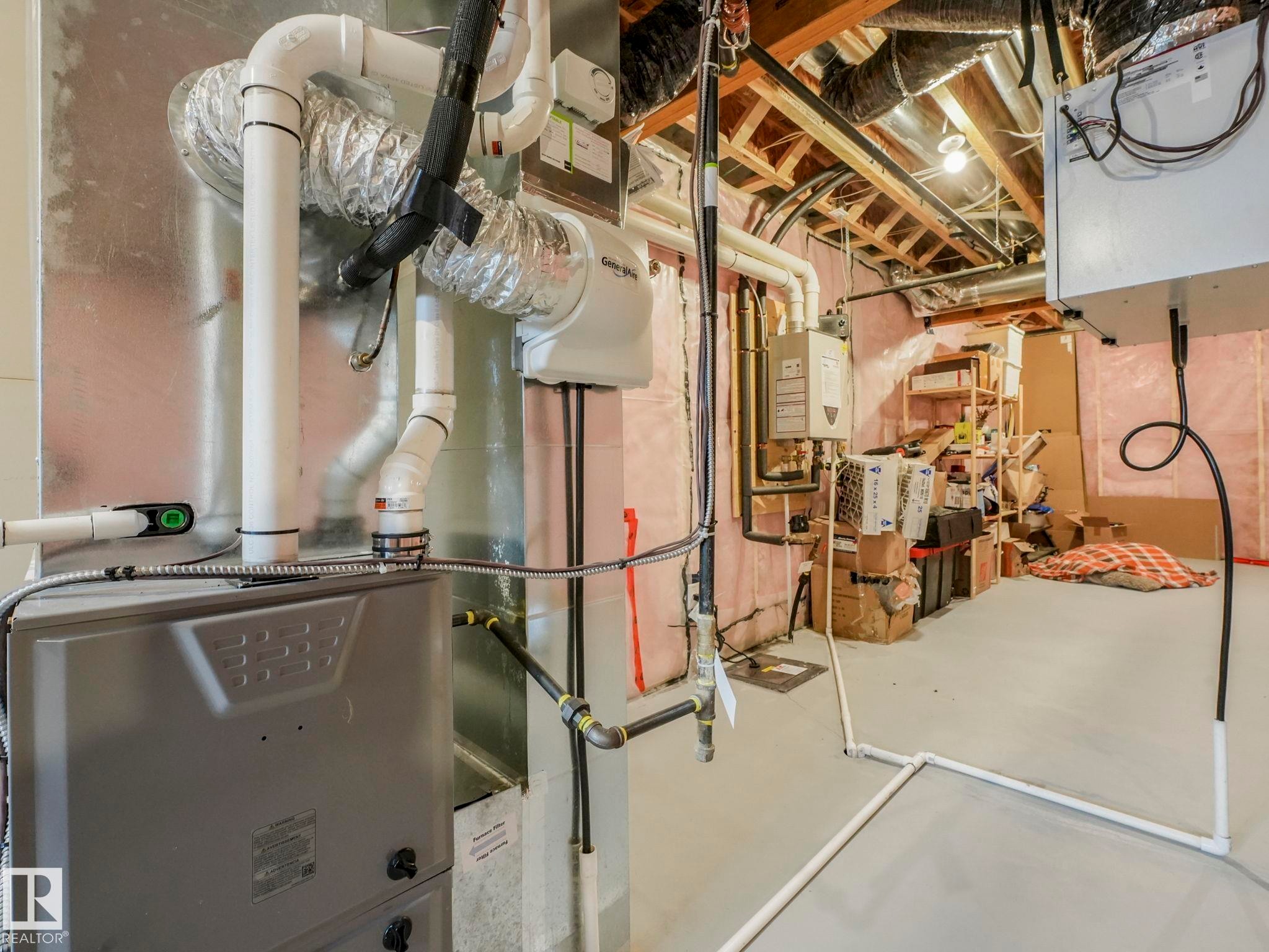 Utility room featuring heating unit and tankless water heater - 4447 Kinsella Green, Edmonton, AB - Indoor Photo Showing Basement