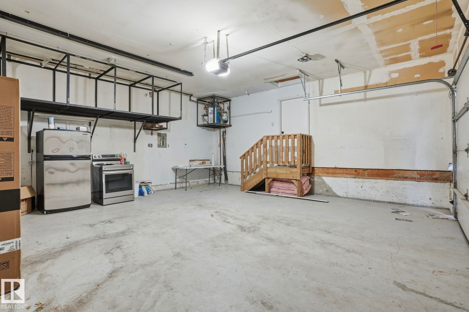Garage with freestanding refrigerator, a garage door opener, and electric panel - 14604 Mackenzie Drive, Edmonton, AB - Indoor Photo Showing Garage