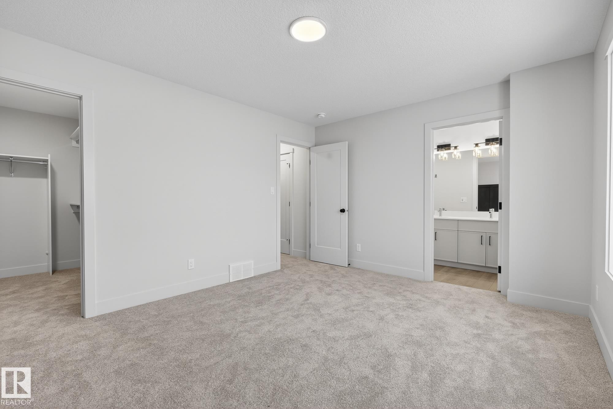 Unfurnished bedroom featuring a spacious closet, light carpet, a textured ceiling, and ensuite bath - 119 Brickyard Drive, Stony Plain, AB - Indoor Photo Showing Other Room