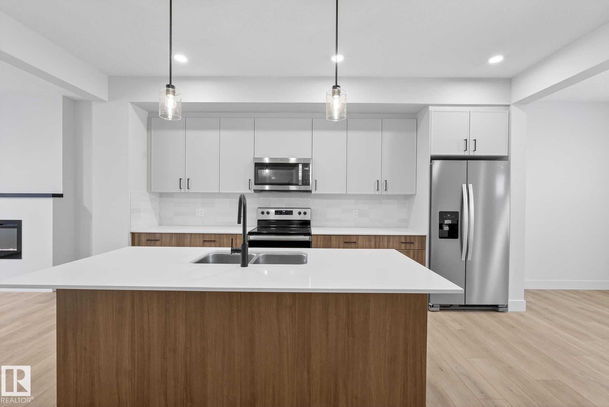 Kitchen with decorative backsplash, white cabinets, stainless steel appliances, pendant lighting, and a center island with sink - 119 Brickyard Drive, Stony Plain, AB - Indoor Photo Showing Kitchen With Double Sink With Upgraded Kitchen