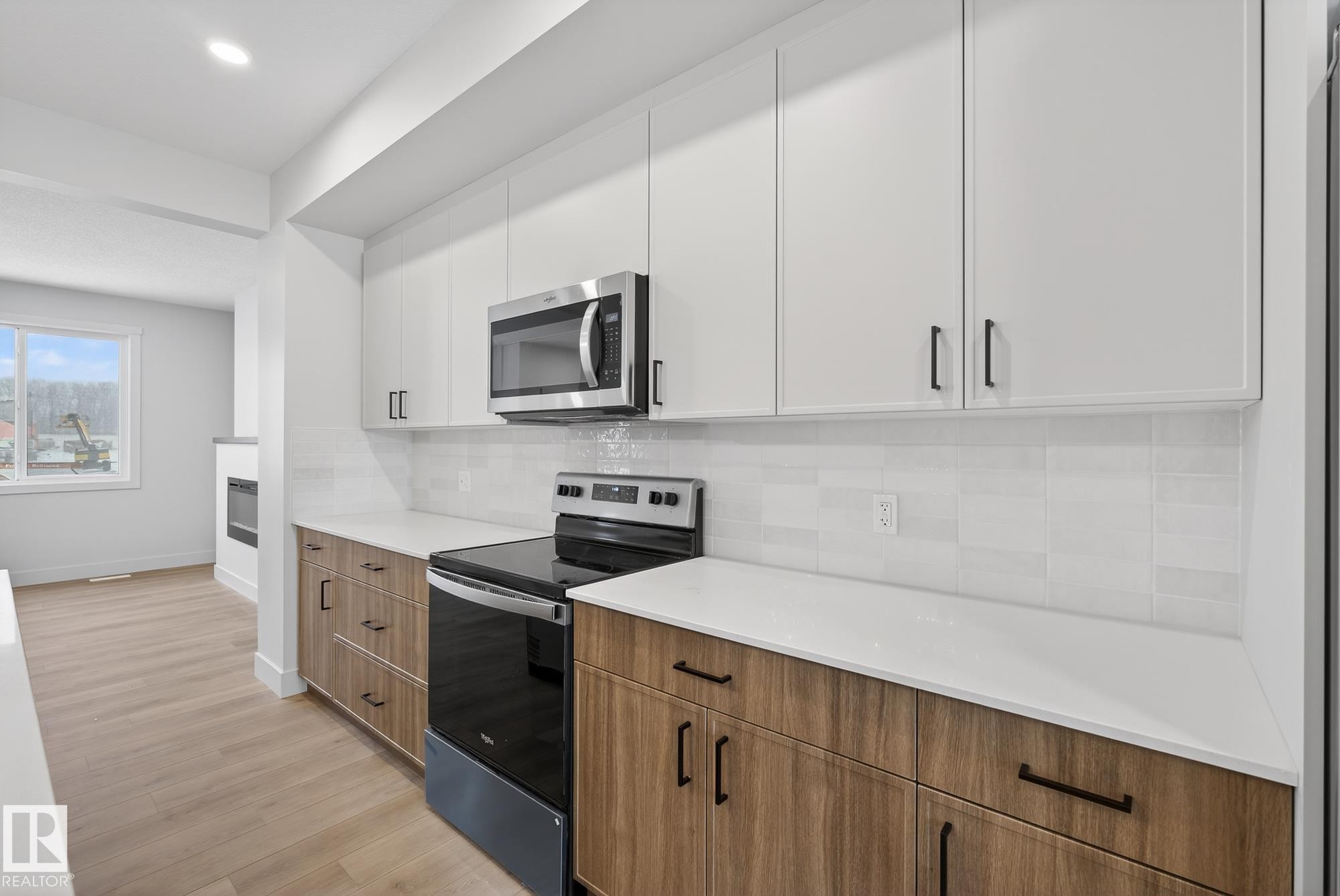Kitchen featuring electric range, modern cabinets, stainless steel microwave, and brown cabinetry - 119 Brickyard Drive, Stony Plain, AB - Indoor Photo Showing Kitchen With Upgraded Kitchen