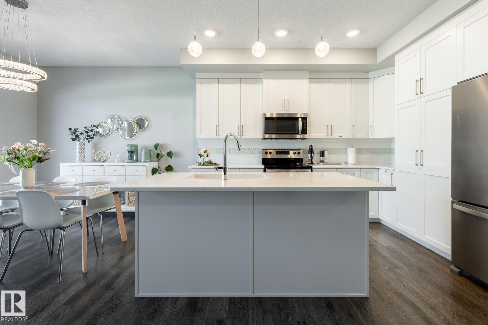Kitchen with stainless steel appliances, backsplash, white cabinets, dark wood finished floors, and light stone counters - 1440 Darby Green, Edmonton, AB - Indoor Photo Showing Kitchen With Upgraded Kitchen