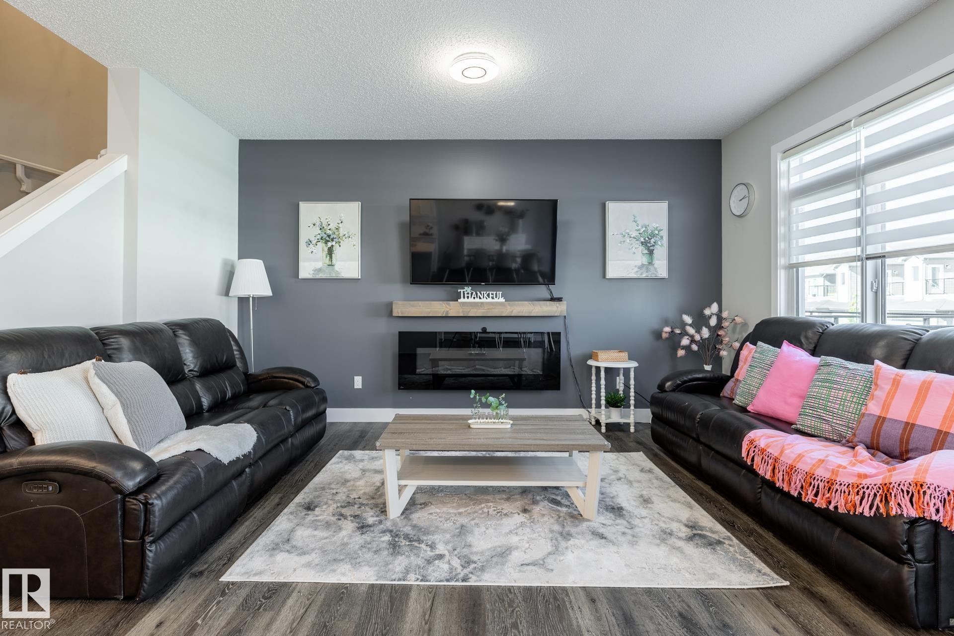 Living area with wood finished floors, a textured ceiling, and a glass covered fireplace - 1440 Darby Green, Edmonton, AB - Indoor Photo Showing Living Room With Fireplace