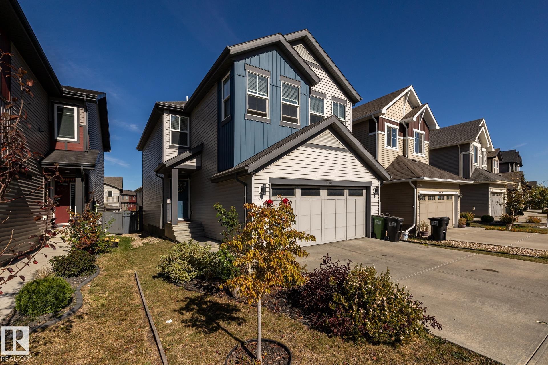 View of front facade featuring board and batten siding, concrete driveway, a residential view, and a front yard - 1440 Darby Green, Edmonton, AB - Outdoor With Facade