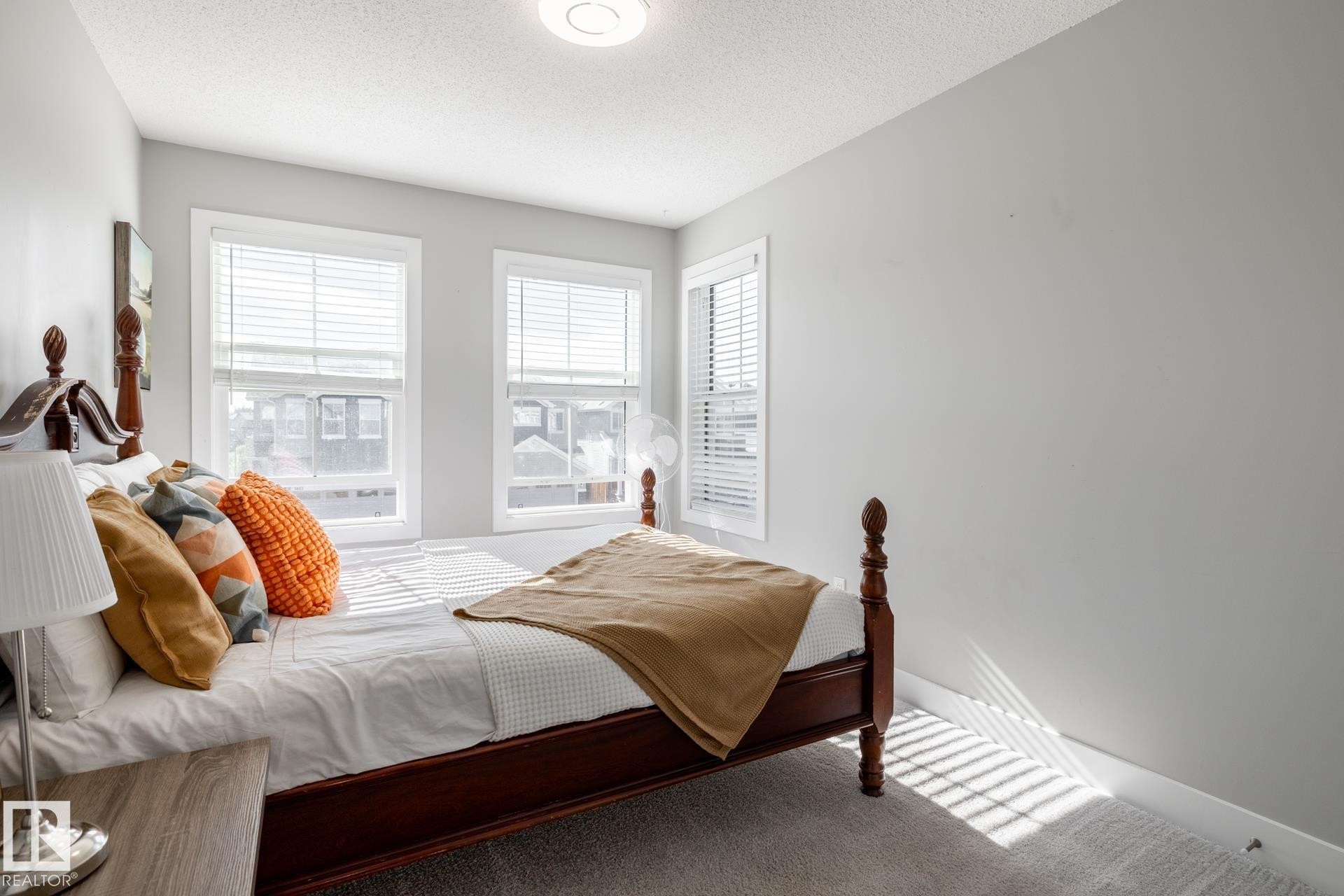 Bedroom with multiple windows, carpet, and a textured ceiling - 1440 Darby Green, Edmonton, AB - Indoor Photo Showing Bedroom