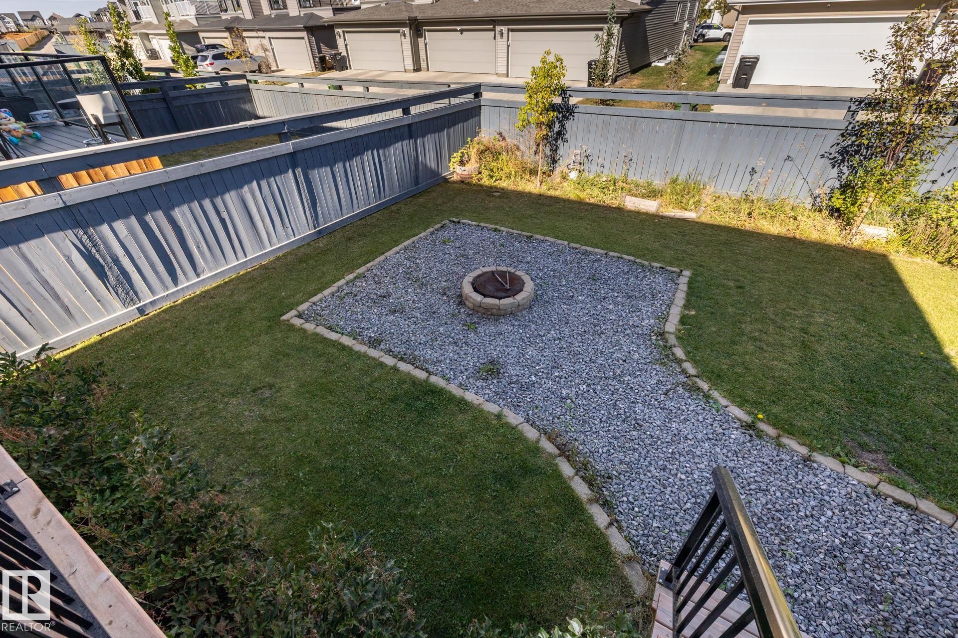 Fenced backyard with a fire pit and a residential view - 1440 Darby Green, Edmonton, AB - Outdoor