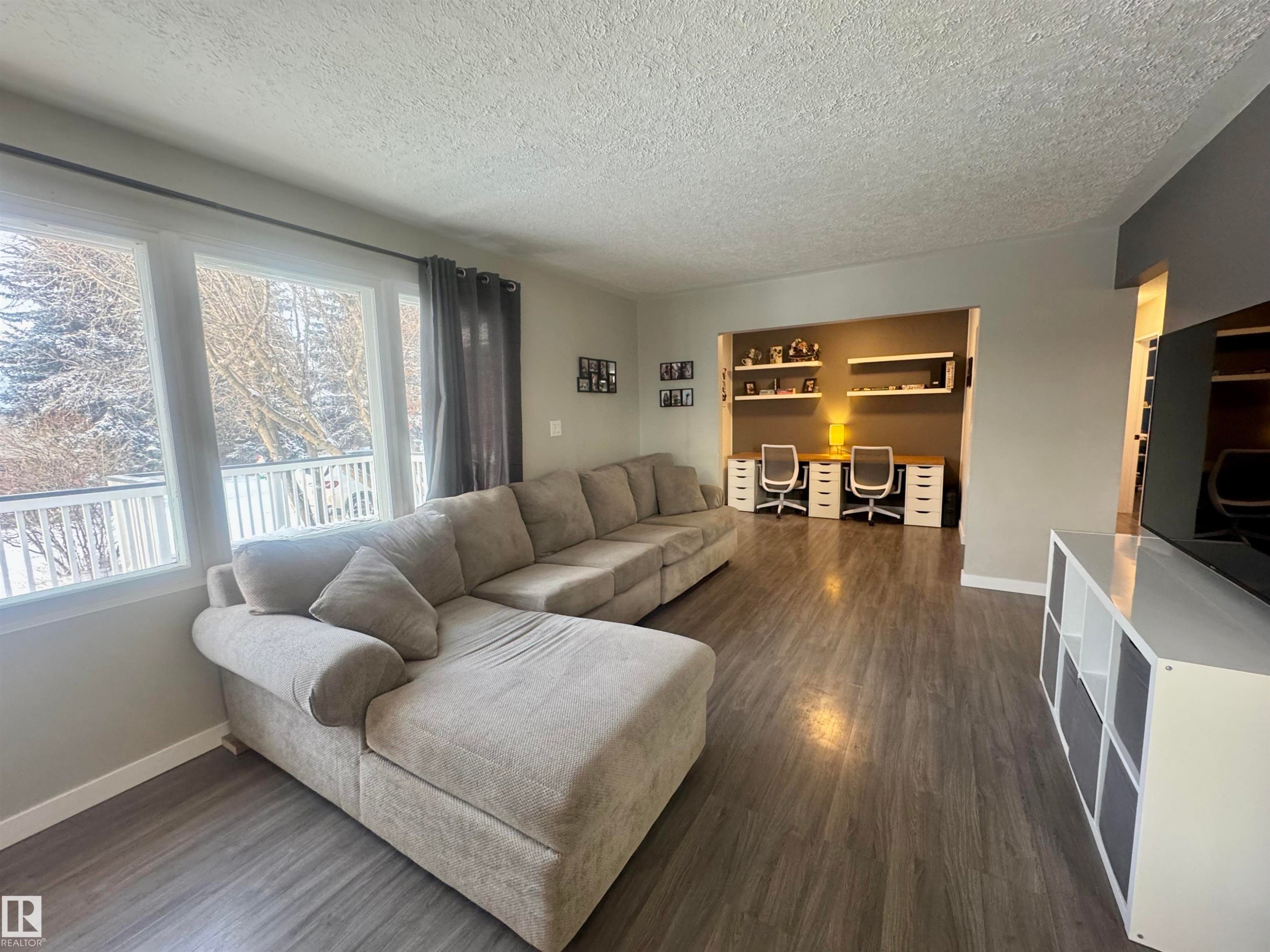 Living room with dark wood finished floors, a textured ceiling, and a desk - 5140 52 Avenue, Ryley, AB - Indoor Photo Showing Living Room