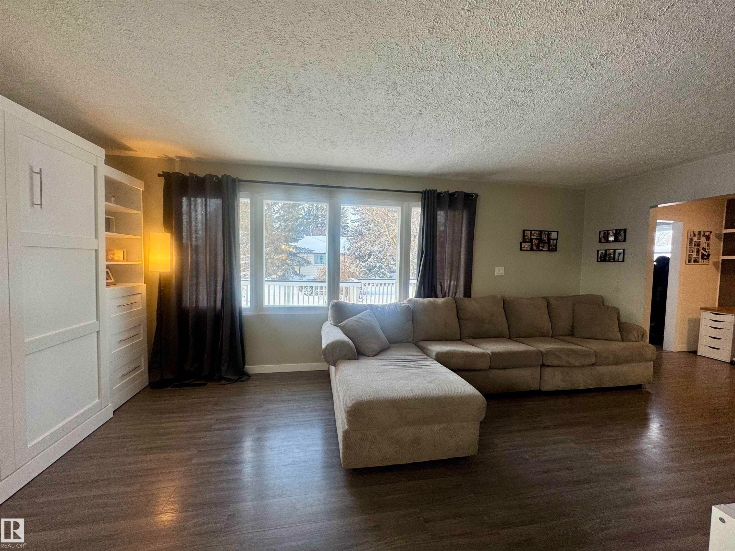 Living room with a textured ceiling and dark wood-style floors - 5140 52 Avenue, Ryley, AB - Indoor Photo Showing Living Room