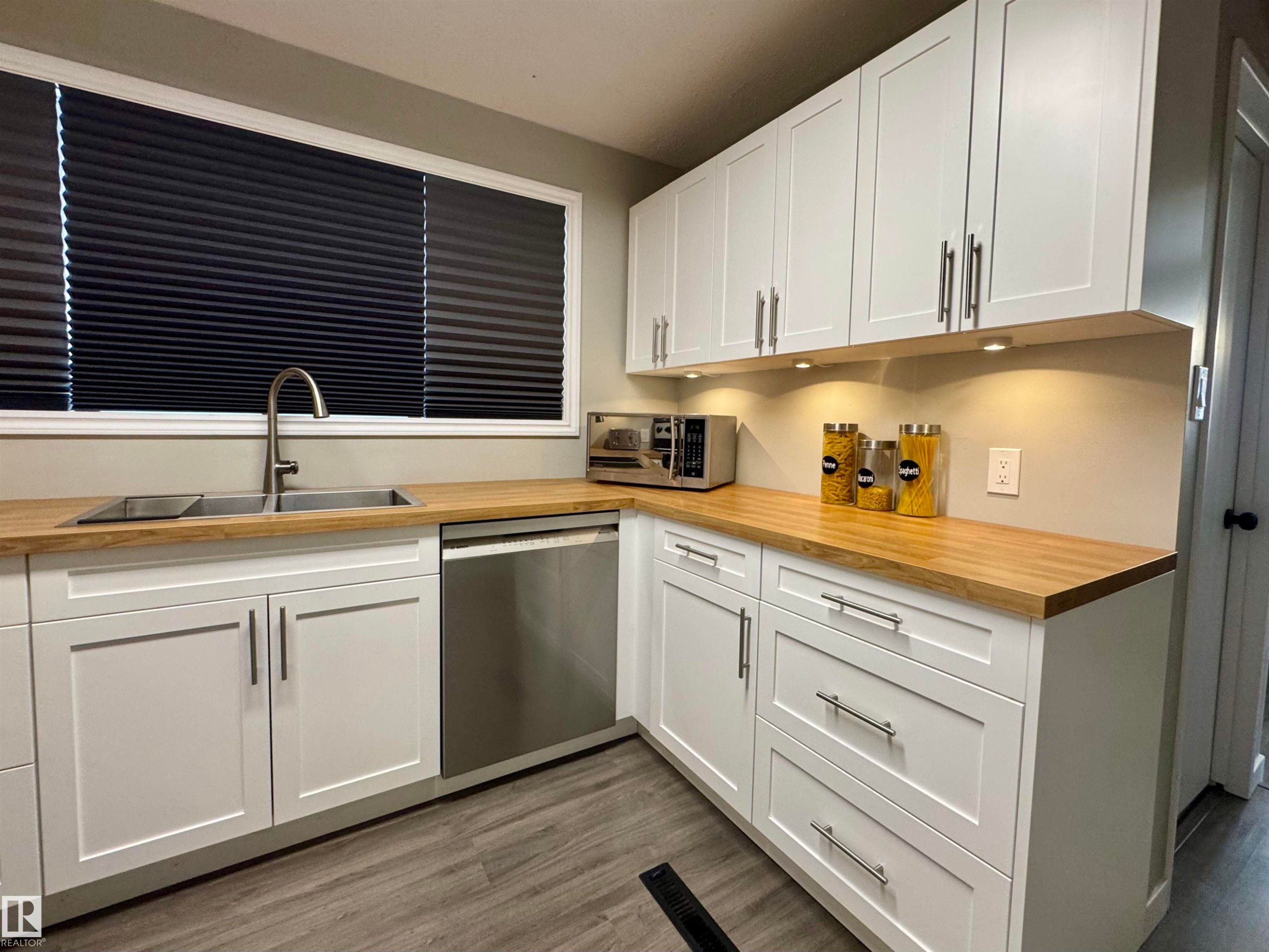 Kitchen featuring white cabinets, wooden counters, and stainless steel appliances - 5140 52 Avenue, Ryley, AB - Indoor Photo Showing Kitchen With Double Sink