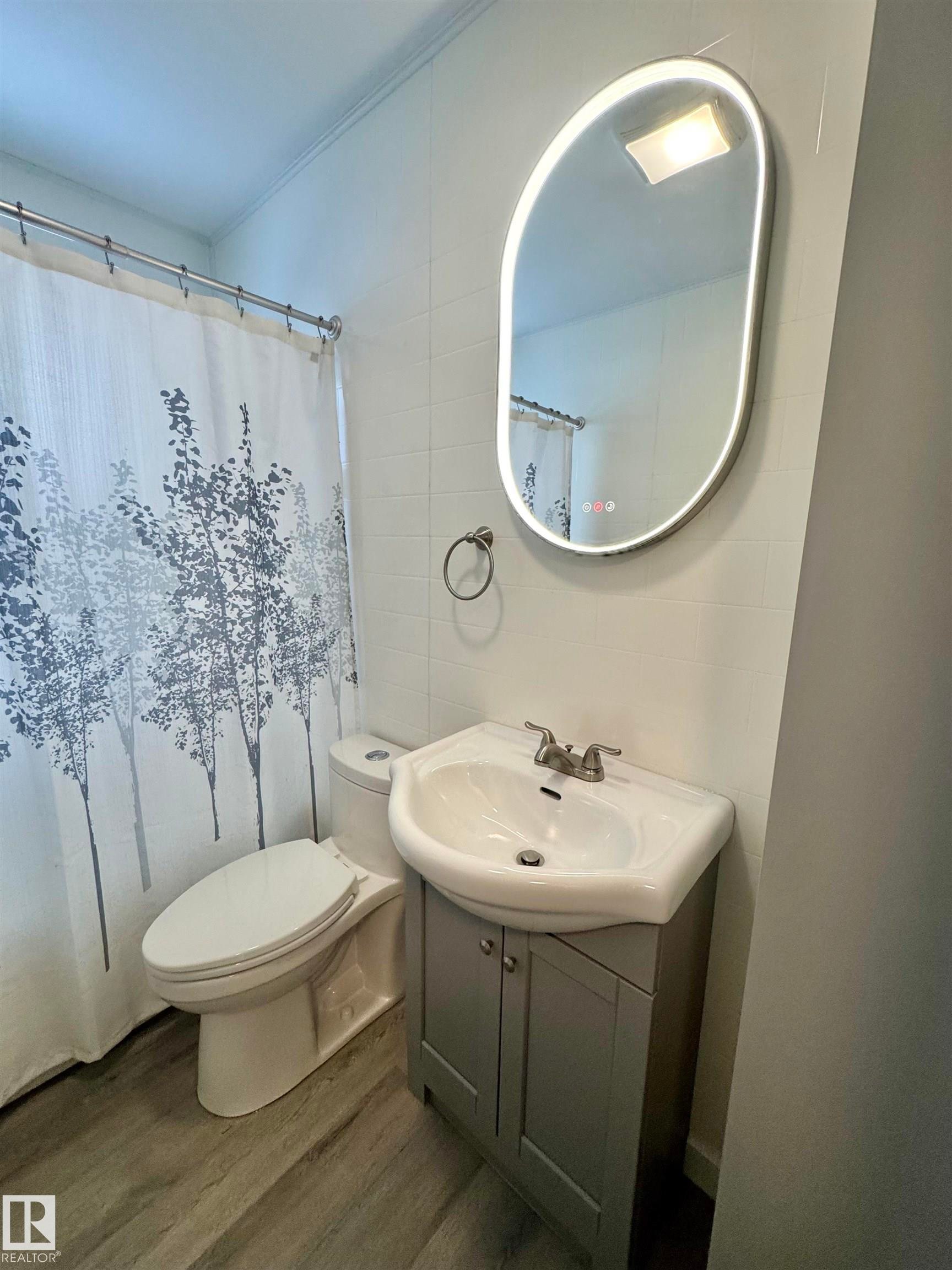Full bath featuring wood finished floors, vanity, and a shower with shower curtain - 5140 52 Avenue, Ryley, AB - Indoor Photo Showing Bathroom