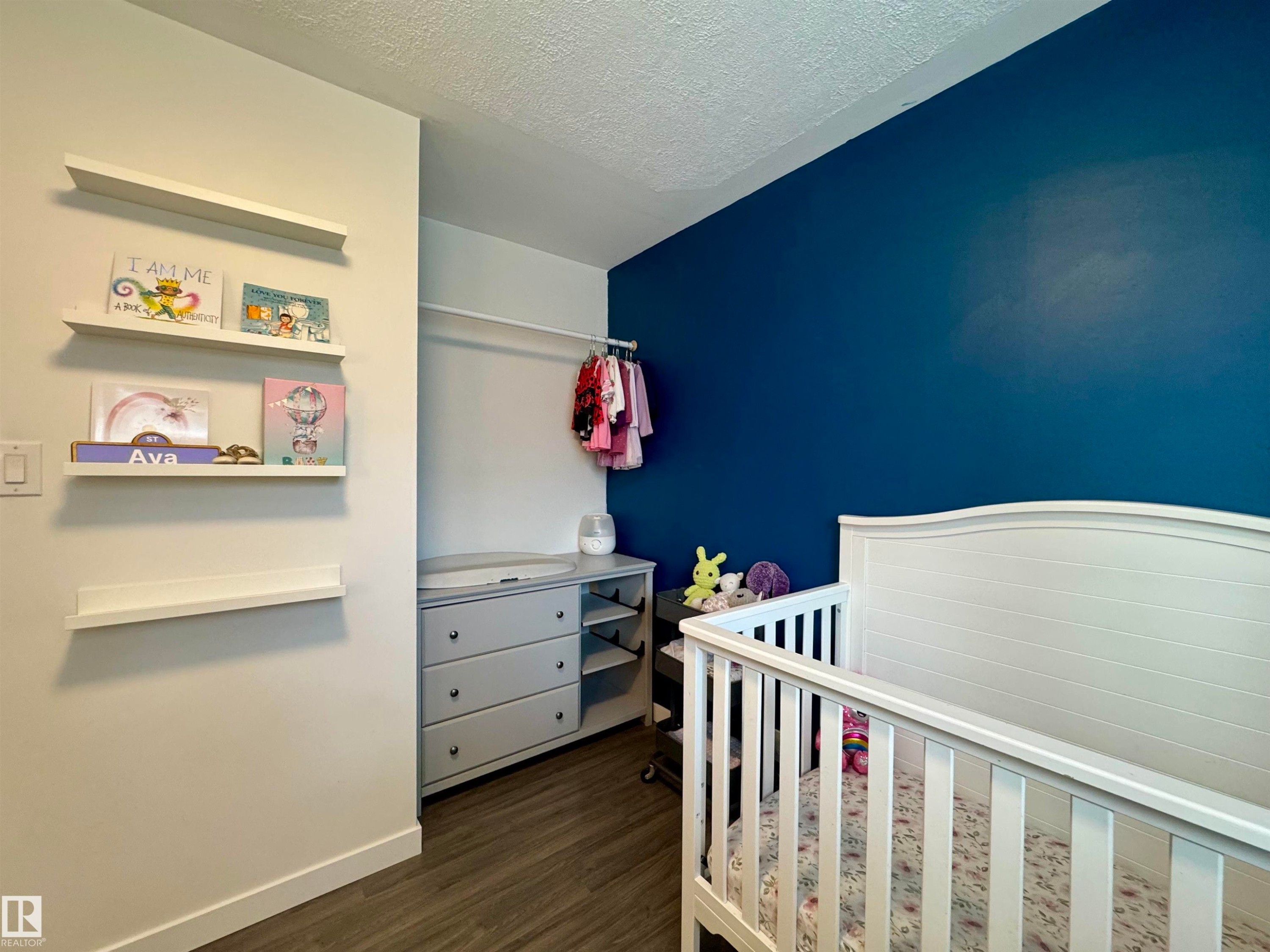 Bedroom with a textured ceiling, dark wood-style flooring, and a nursery area - 5140 52 Avenue, Ryley, AB - Indoor Photo Showing Bedroom