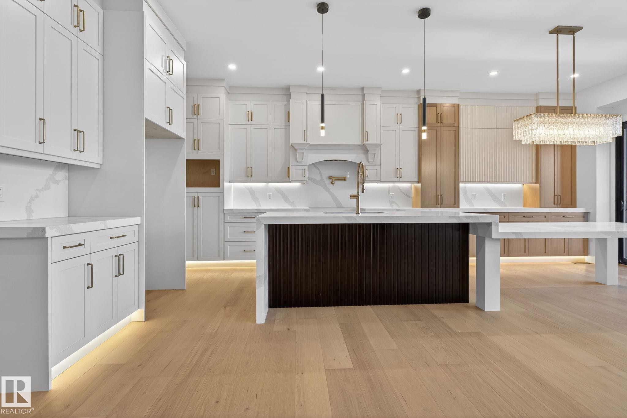 Kitchen featuring a kitchen island with sink, light stone counters, pendant lighting, a breakfast bar area, and light wood-style flooring - 1926 Ainslie Link, Edmonton, AB - Indoor Photo Showing Kitchen With Upgraded Kitchen