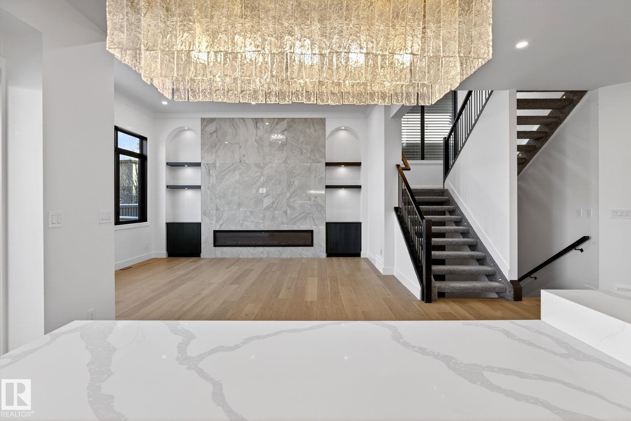 Unfurnished living room with built in features, a fireplace, light wood-style flooring, stairs, and recessed lighting - 1926 Ainslie Link, Edmonton, AB - Indoor Photo Showing Other Room