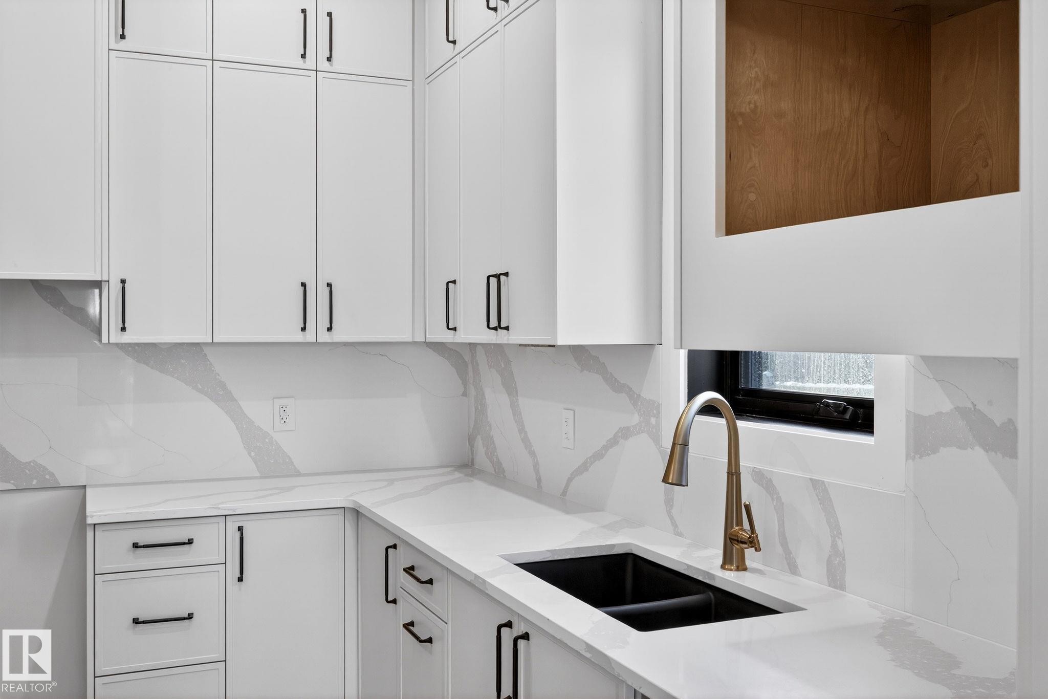 Kitchen with white cabinets, light stone counters, and tasteful backsplash - 1926 Ainslie Link, Edmonton, AB - Indoor Photo Showing Kitchen With Double Sink