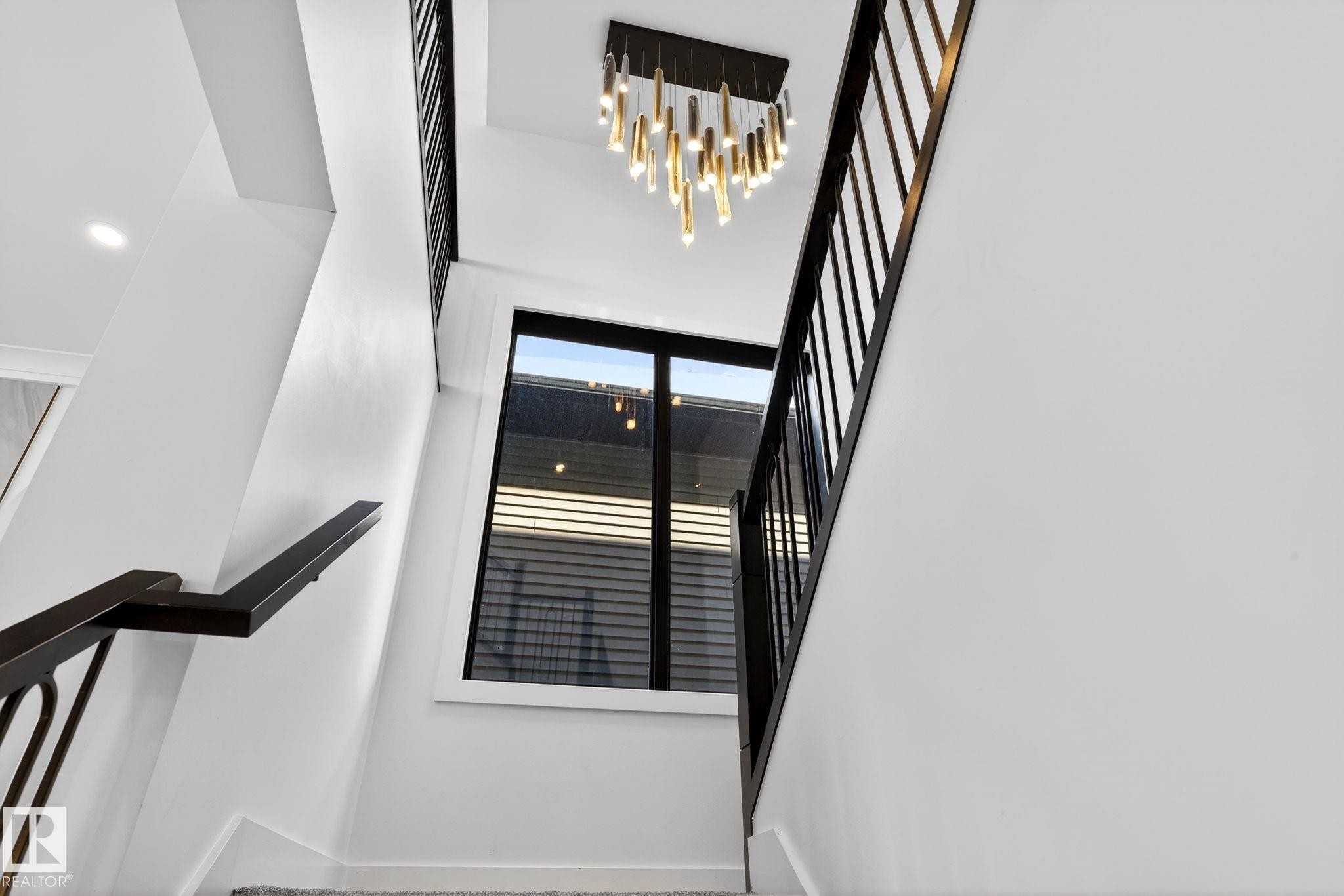 Stairs with a chandelier and a high ceiling - 1926 Ainslie Link, Edmonton, AB - Indoor Photo Showing Other Room