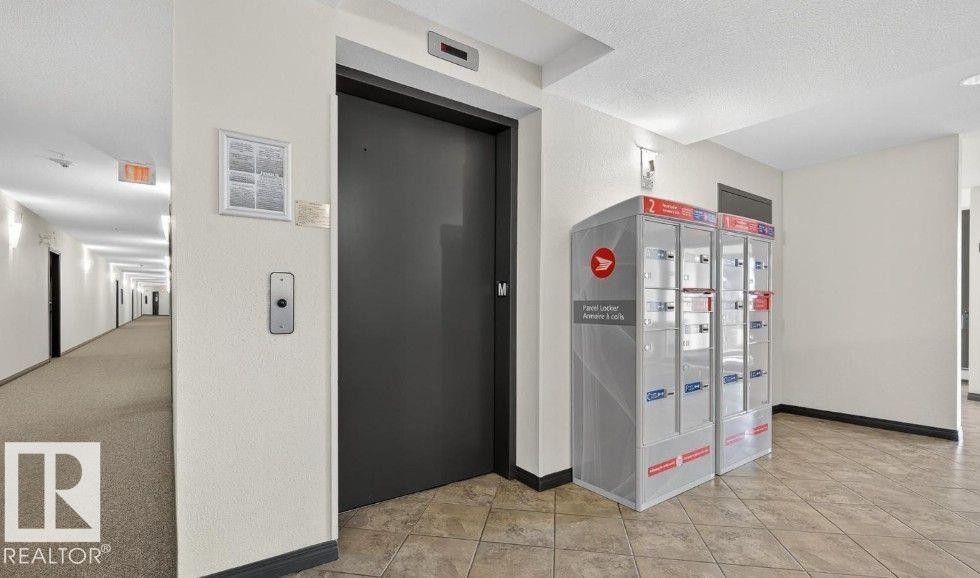Interior space with elevator, a textured ceiling, and light tile patterned flooring - 231 1180 Hyndman Road, Edmonton, AB - Indoor Photo Showing Other Room