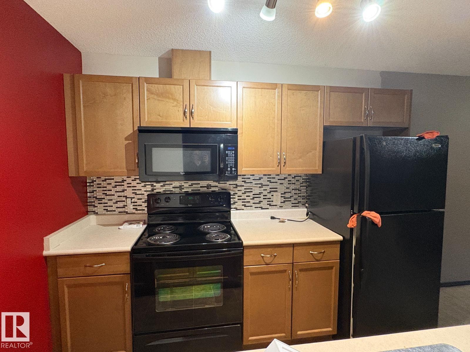 Kitchen with black appliances, light countertops, and tasteful backsplash - 231 1180 Hyndman Road, Edmonton, AB - Indoor Photo Showing Kitchen