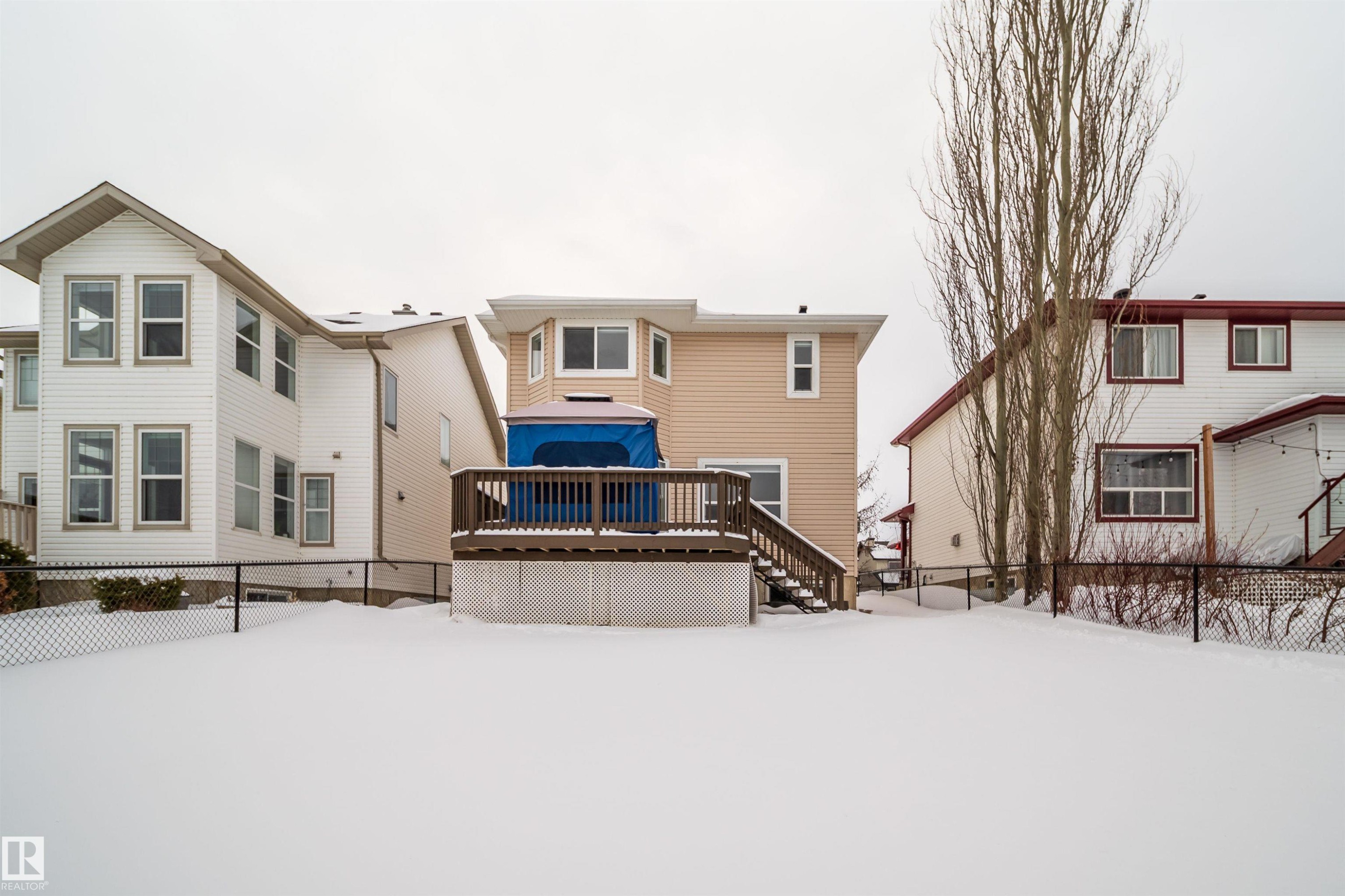 Snow covered house featuring a fenced backyard, a wooden deck, and stairway - 8518 6 Av, Edmonton, AB - Outdoor