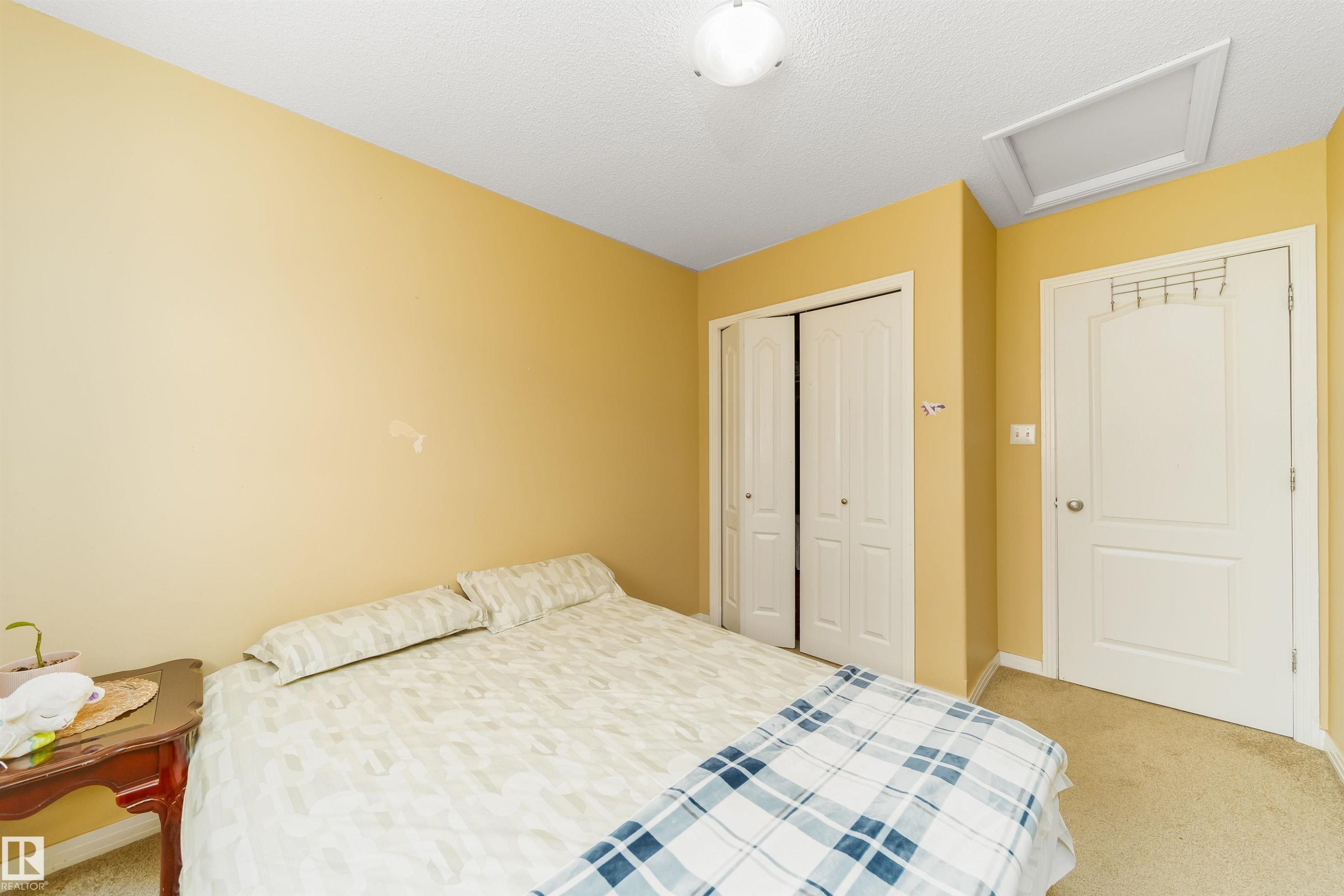 Bedroom with attic access, light carpet, a closet, and a textured ceiling - 8518 6 Av, Edmonton, AB - Indoor Photo Showing Bedroom